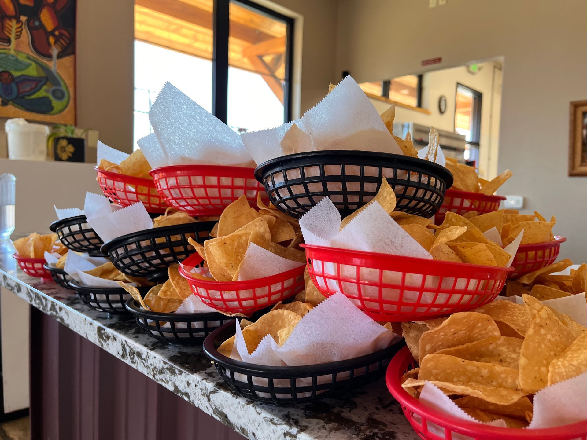 A stack of baskets filled with tortilla chips on a counter.