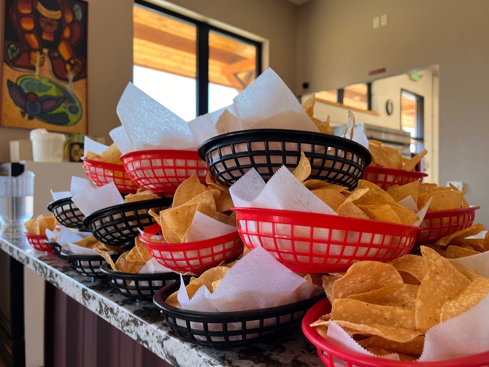A stack of baskets filled with tortilla chips on a counter.