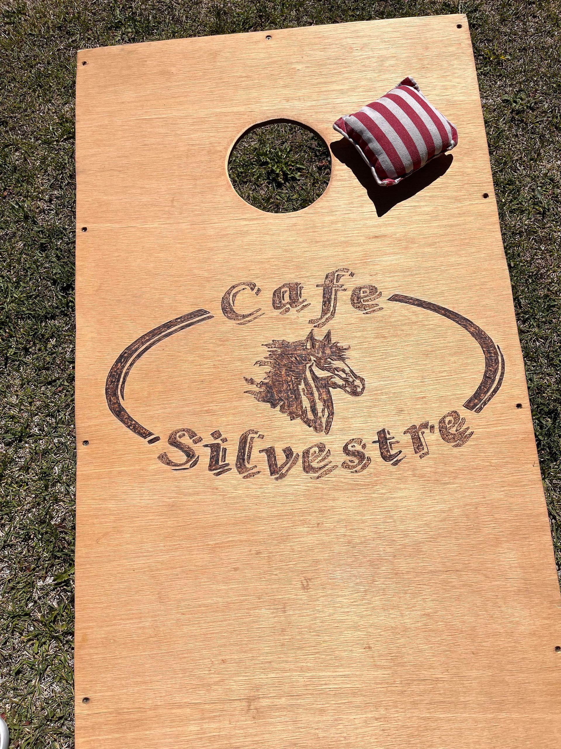 A cornhole board with a horse on it is sitting on top of a lush green field.