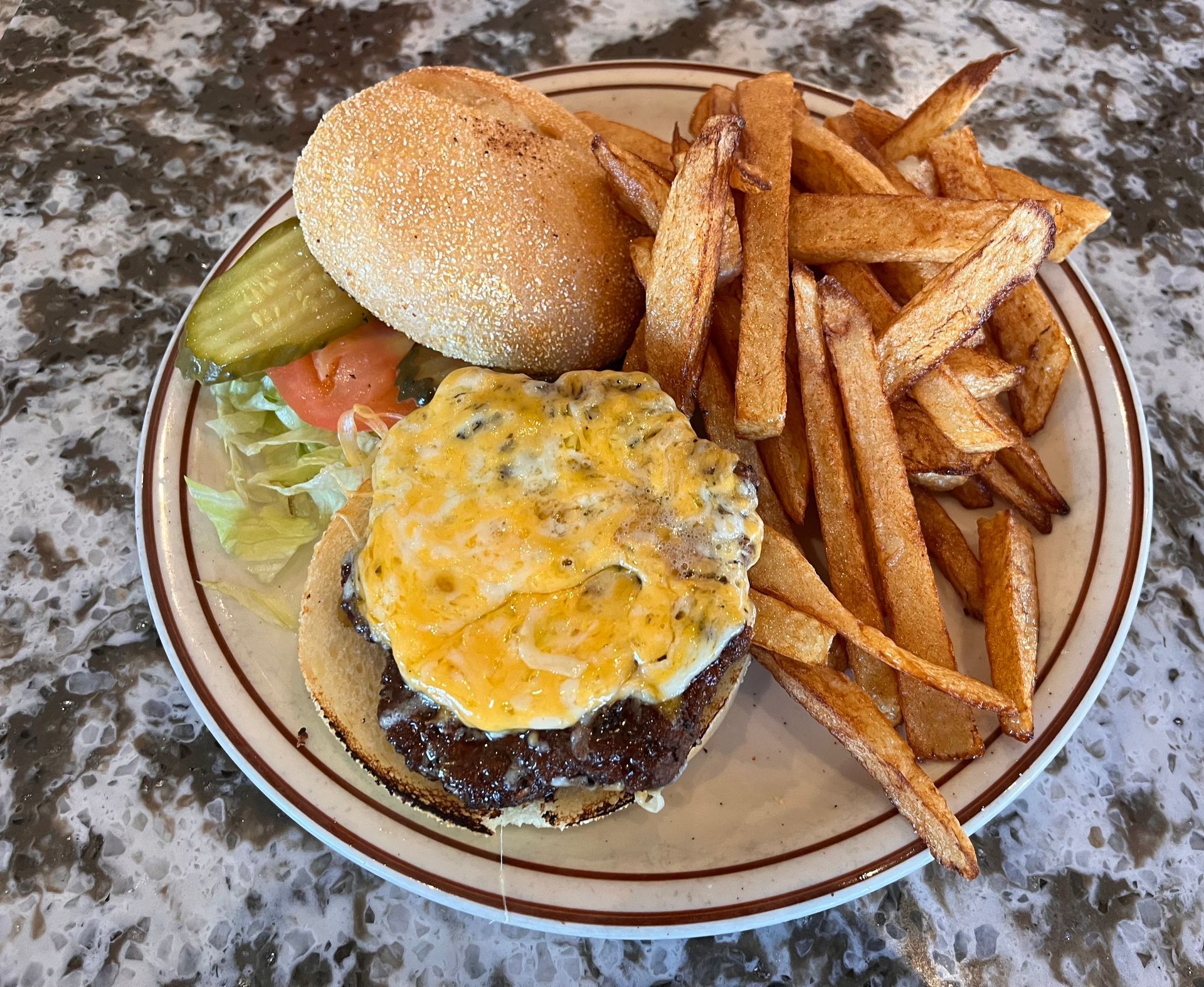 A plate of food with a hamburger and french fries on a table.