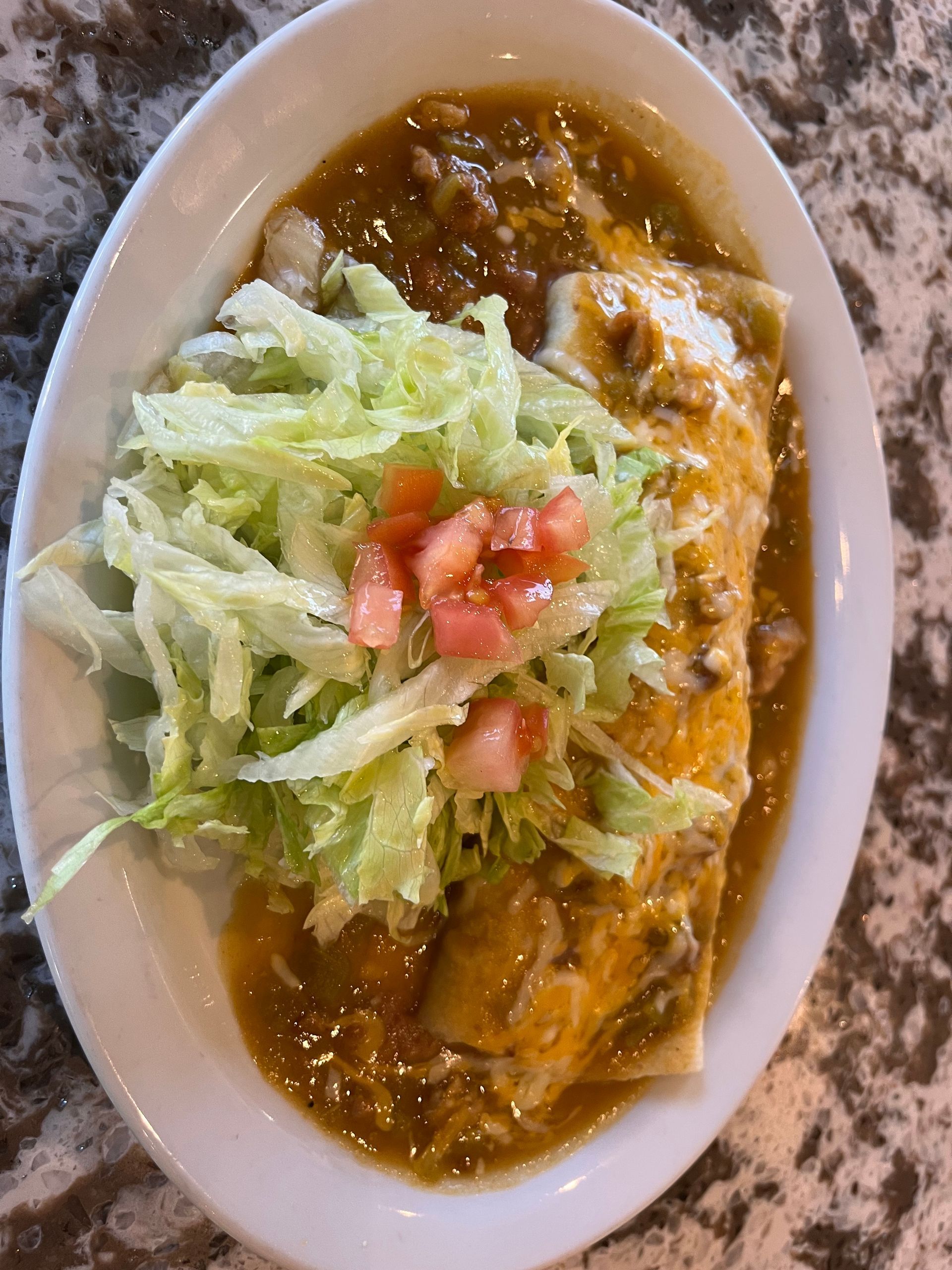 A white plate topped with a burrito and lettuce on a table.