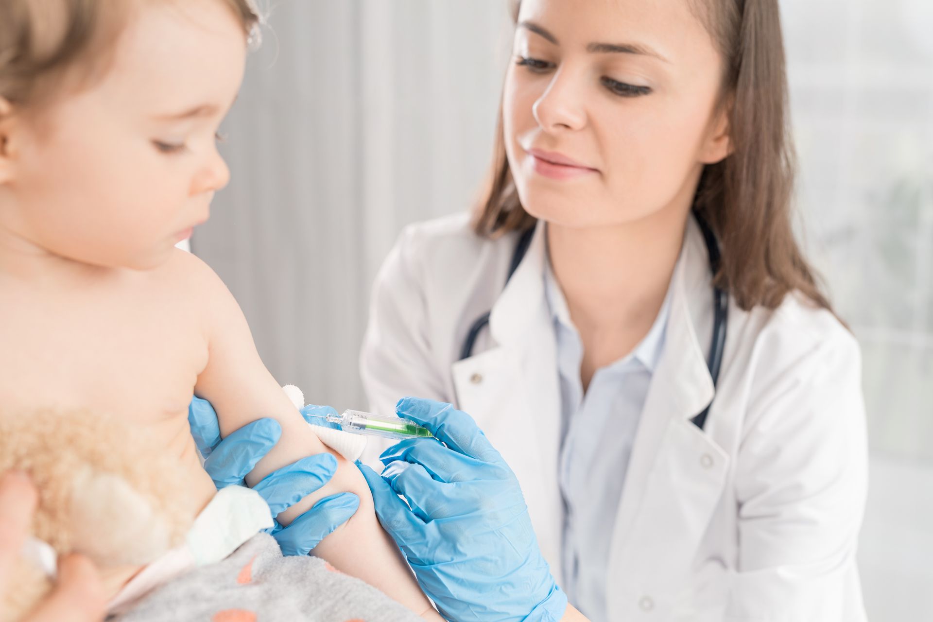 A doctor is giving a baby an injection in his arm.