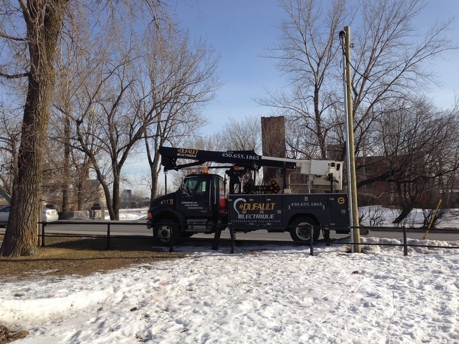 Un camion avec une grue dessus est garé dans la neige.