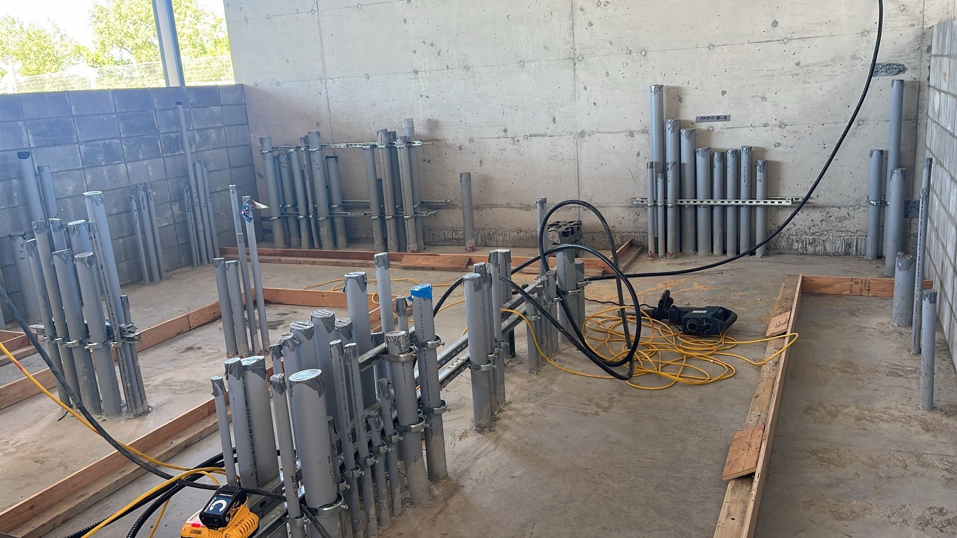 Une pièce avec beaucoup de tuyaux et une perceuse au sol.