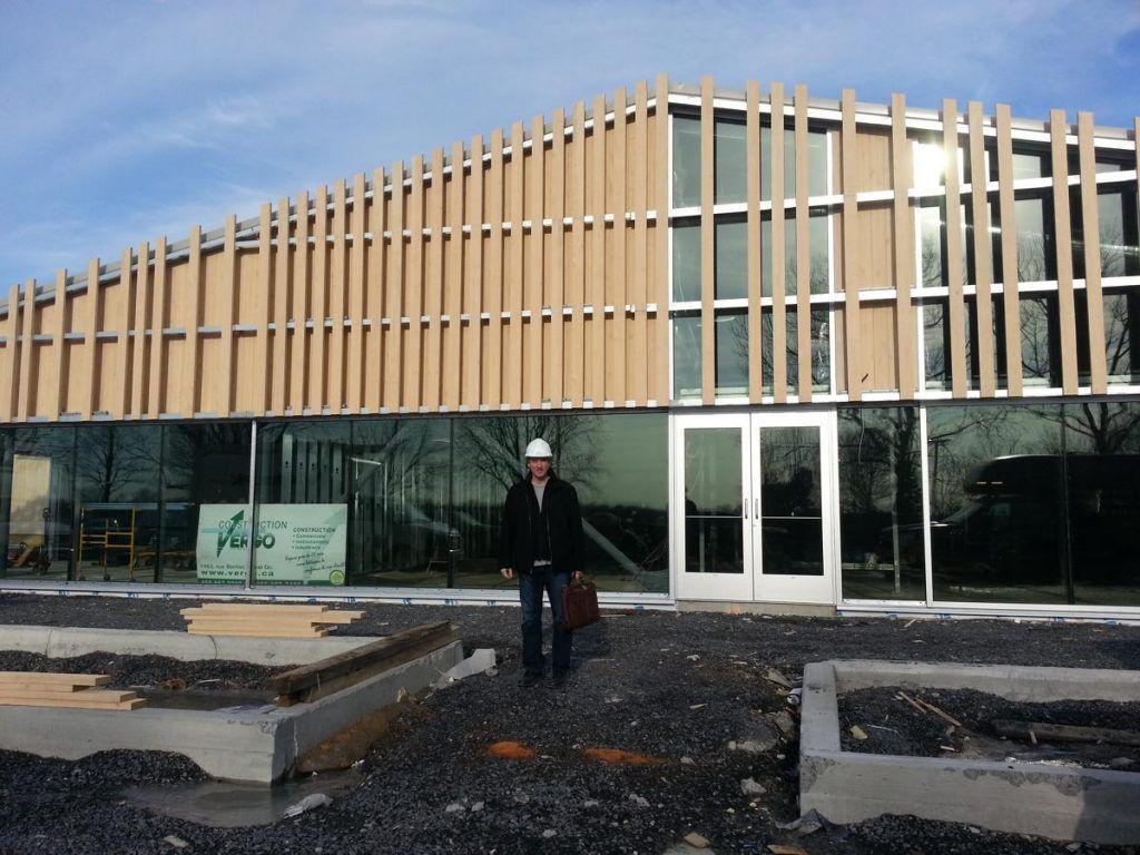 Un homme portant un casque de chantier se tient devant un bâtiment en construction