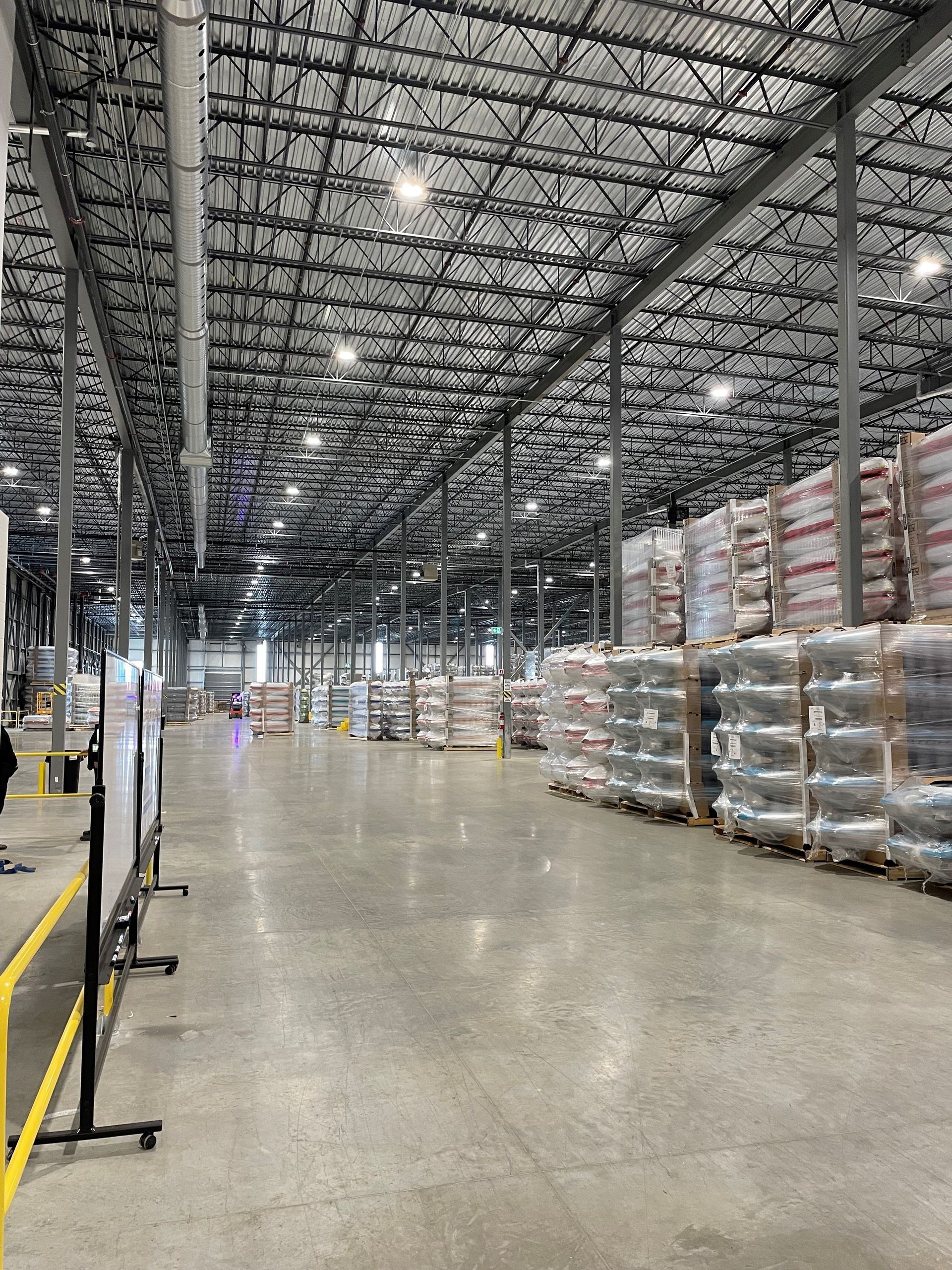 Un grand entrepôt rempli de nombreuses palettes et cartons.