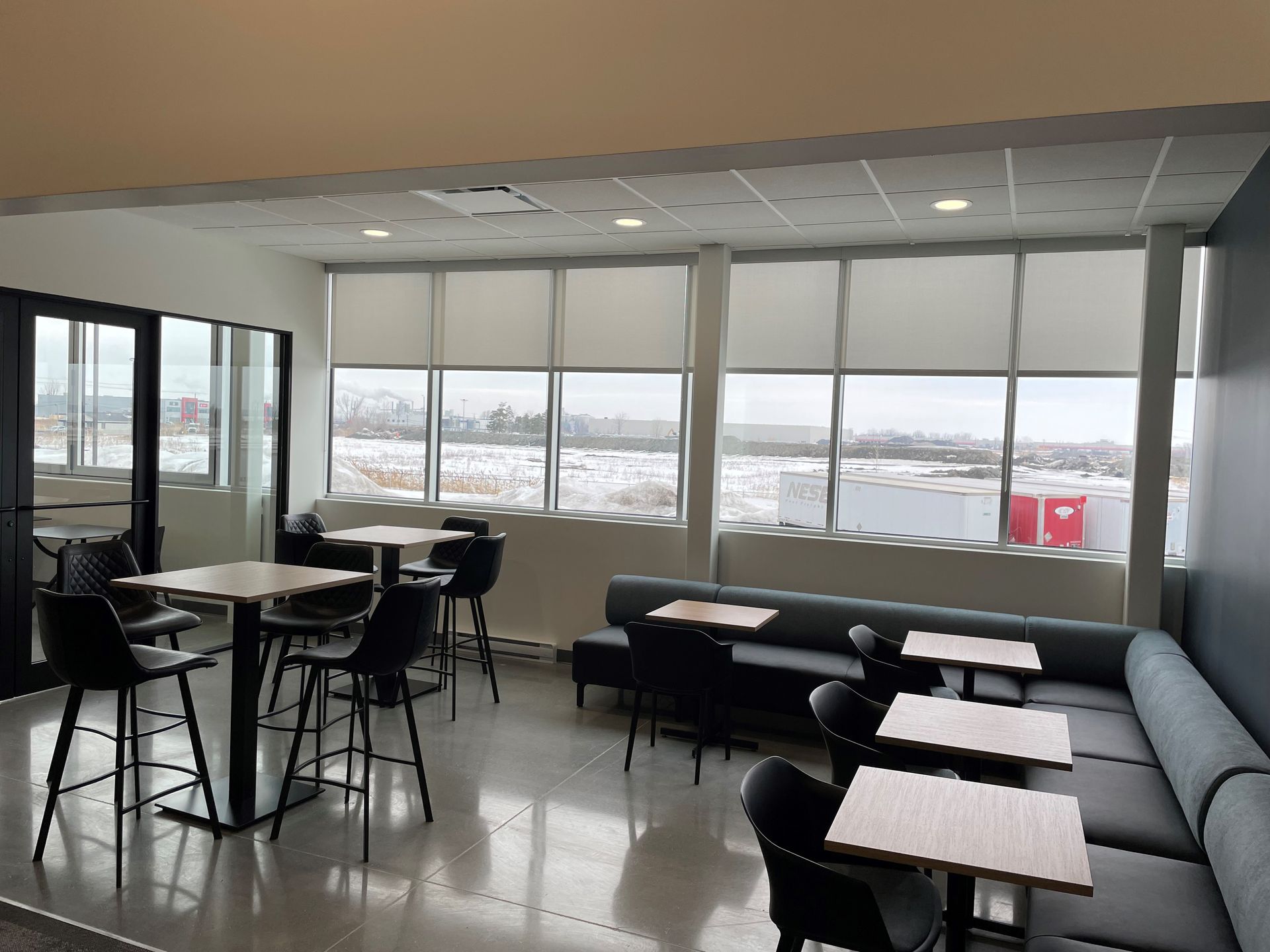 Une pièce avec des tables et des chaises et une grande fenêtre.