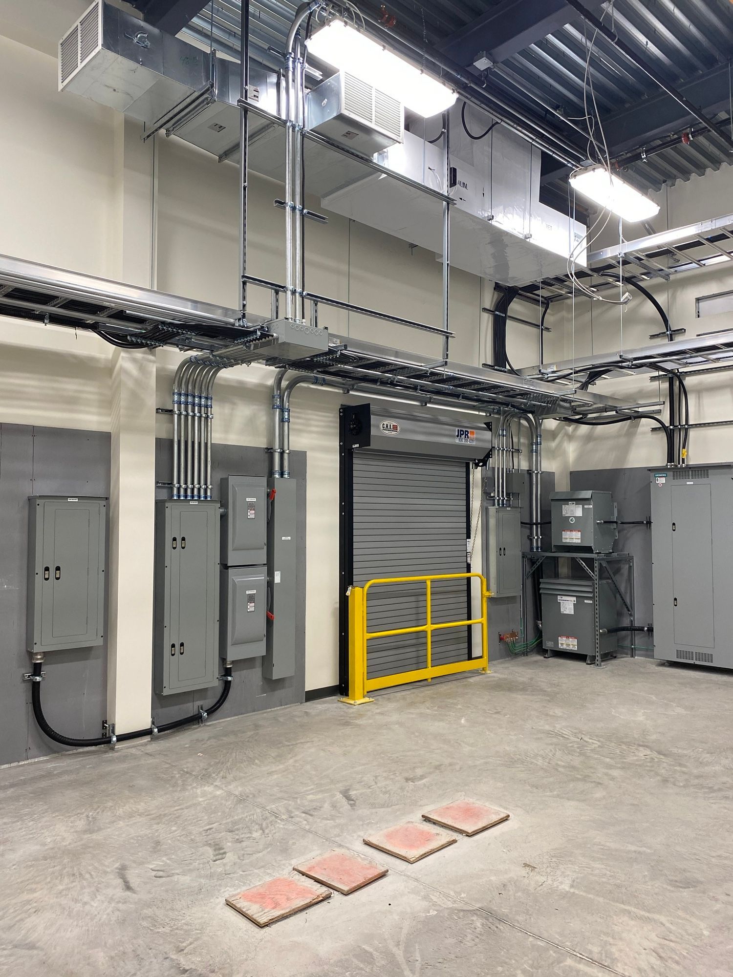 Une grande pièce avec beaucoup d'équipements électriques et une barrière jaune.