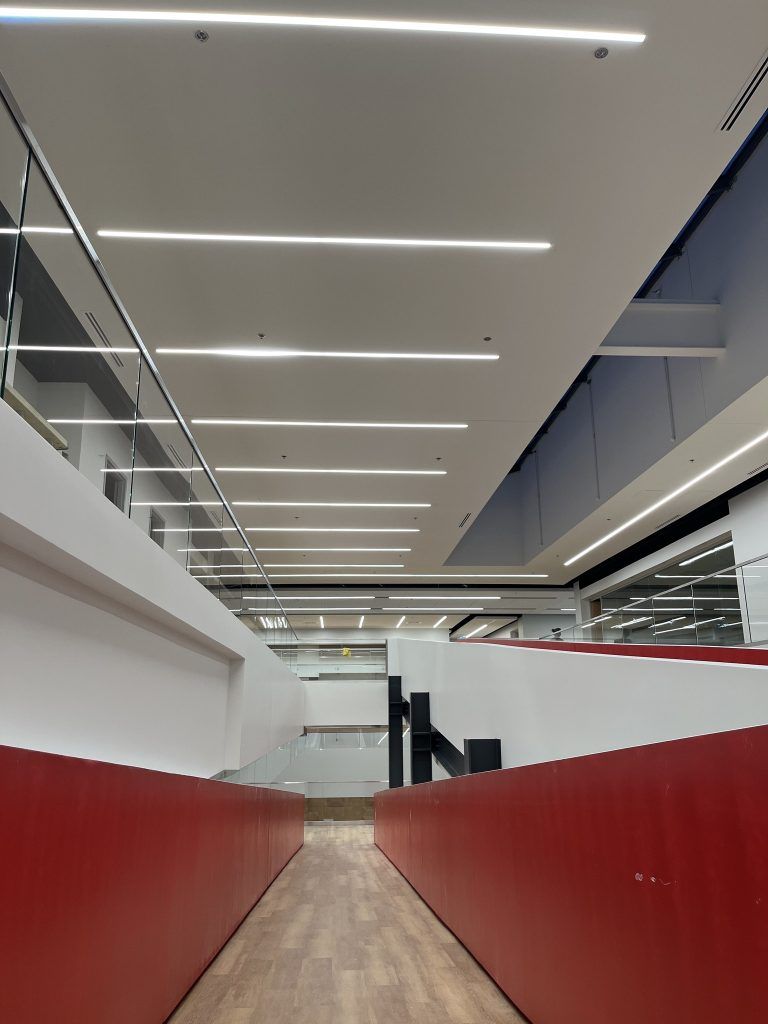 Un long couloir avec des murs rouges et un plafond avec beaucoup de lumières