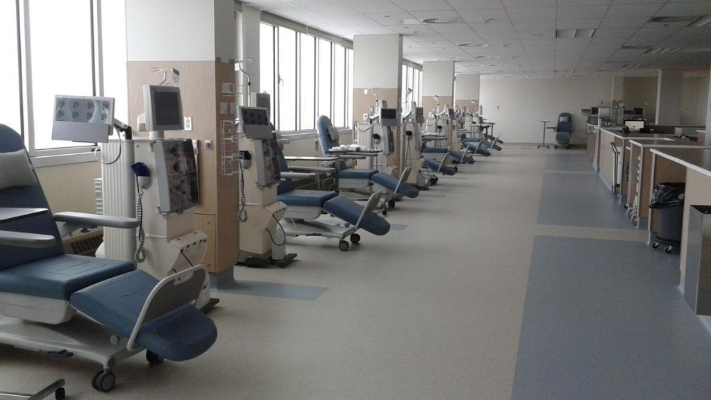 Une rangée de machines de dialyse est alignée dans une chambre d'hôpital.