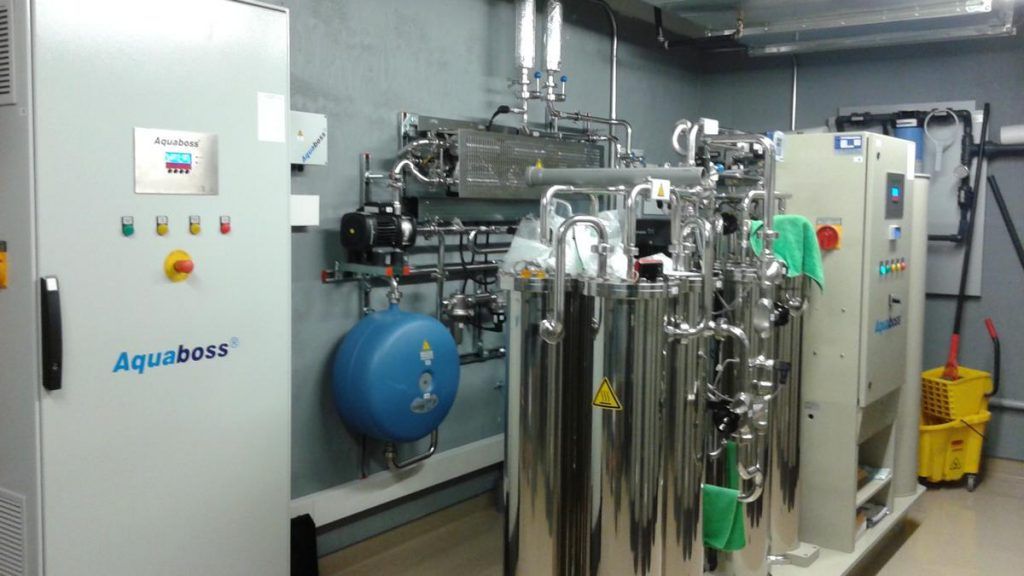 Une pièce avec beaucoup de cuves en acier inoxydable et une serpillière jaune.