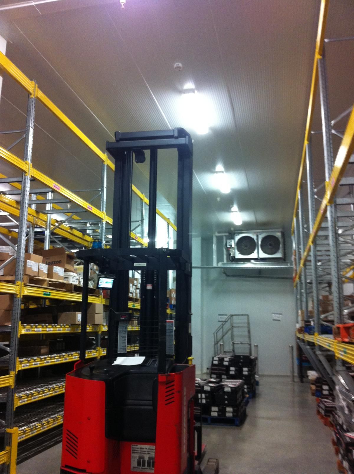 Un chariot élévateur rouge se trouve dans un grand entrepôt