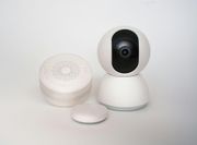 White security camera and speaker with a small, round button on a white background.