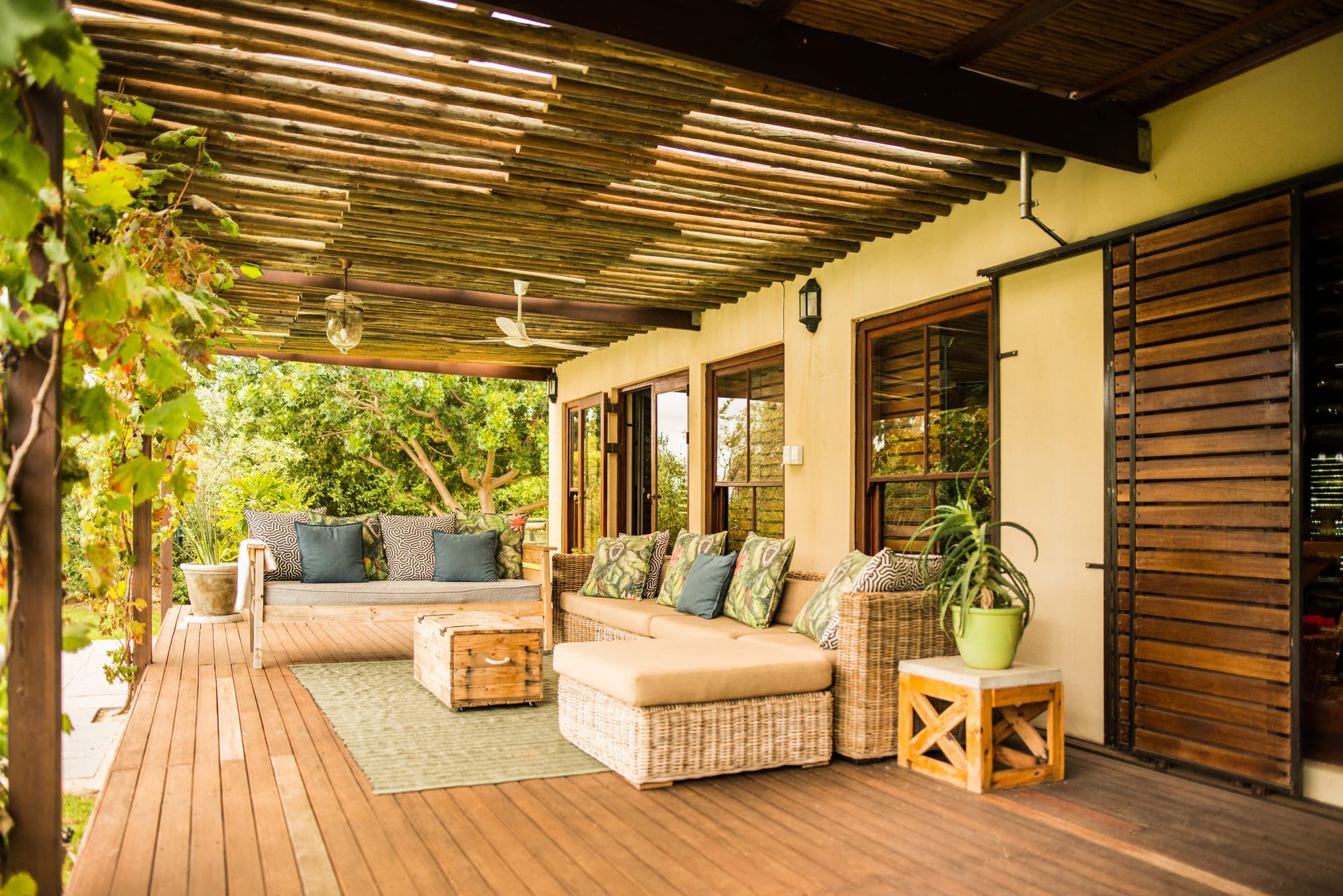 A wooden deck with a couch and chairs under a pergola.