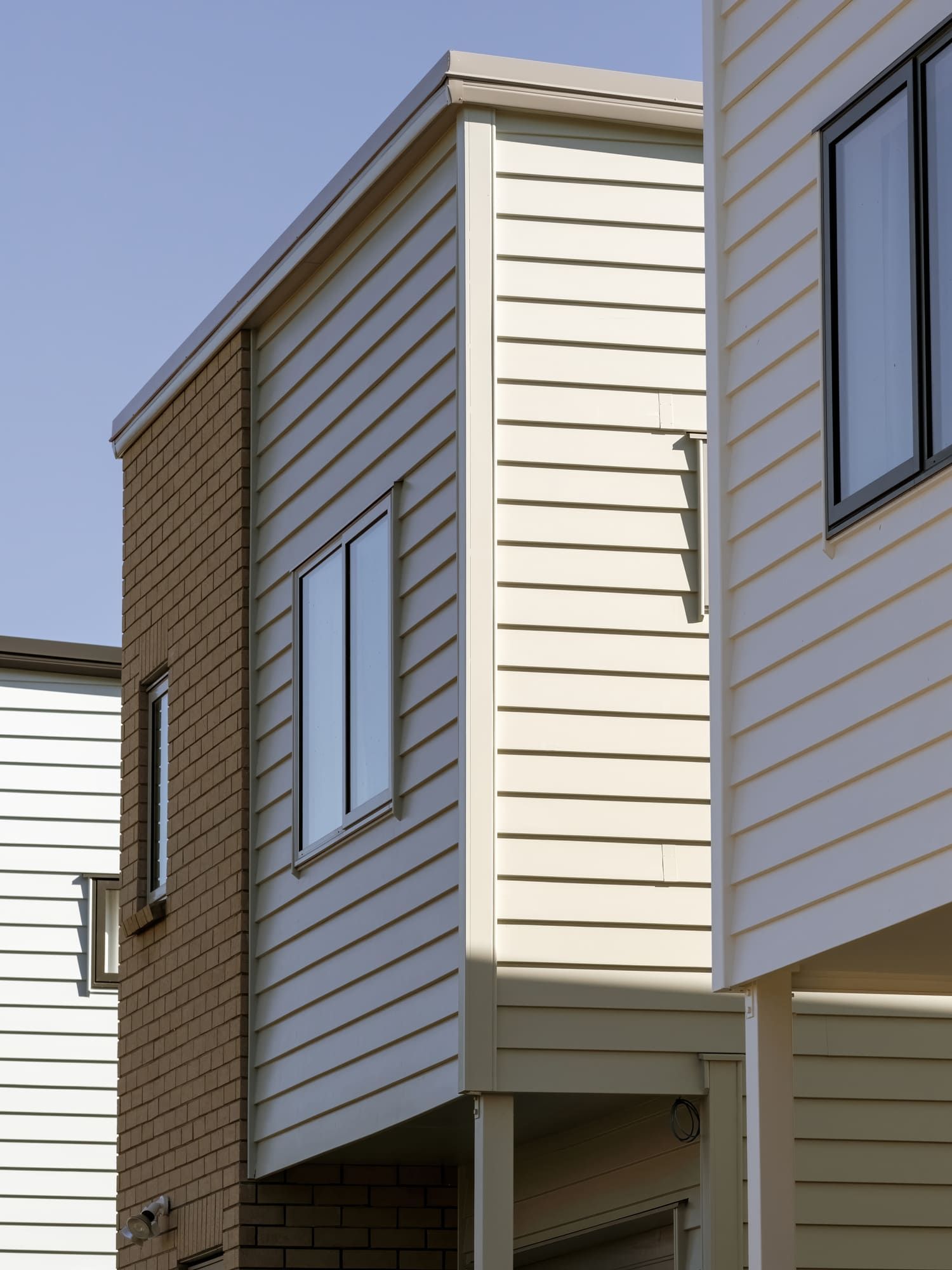 A row of houses with white siding and black windows