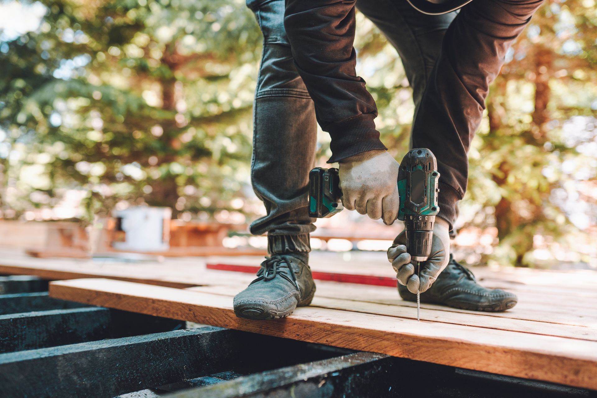 A man is using a drill to drill a hole in a piece of wood.