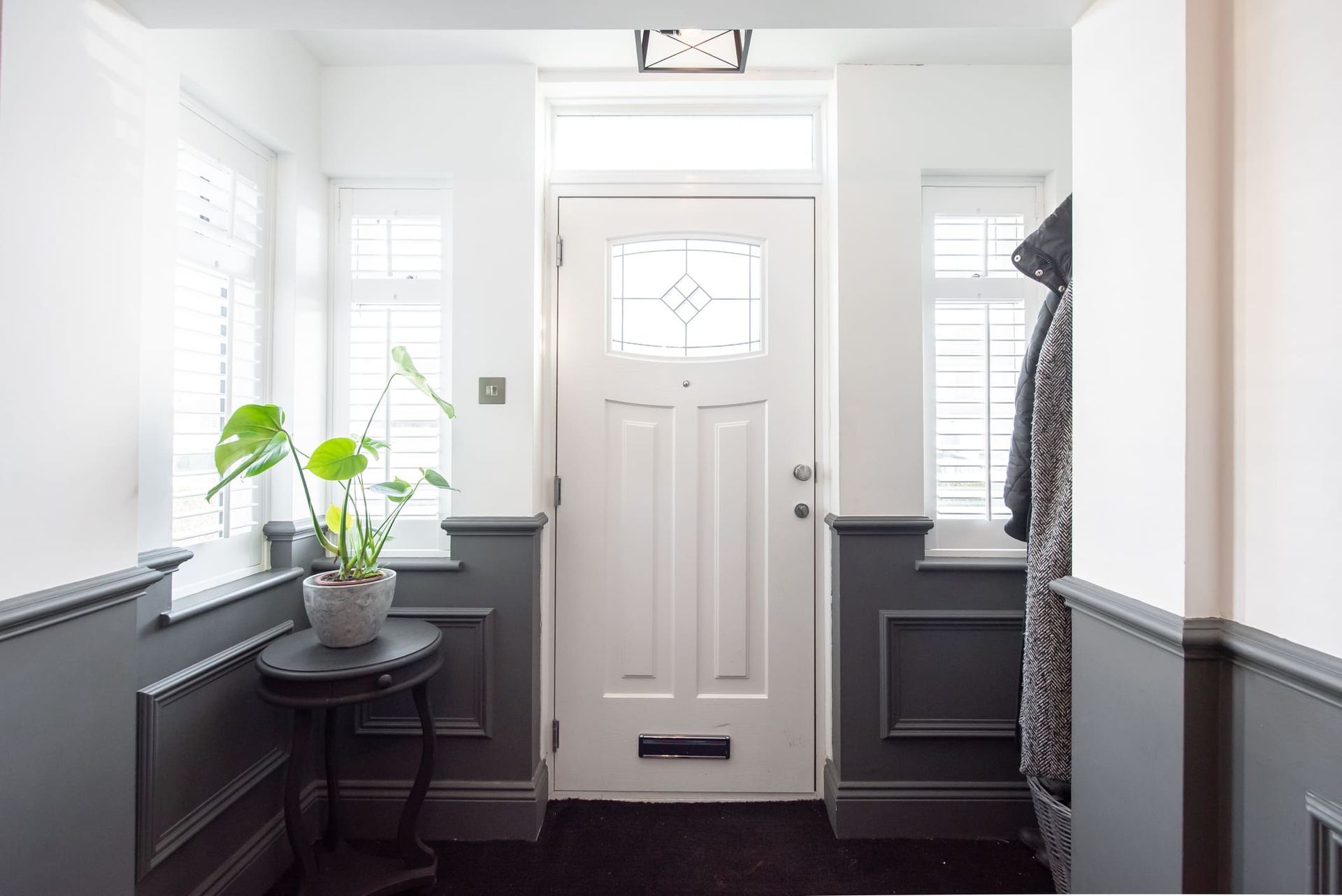 A hallway with a white door and a potted plant on a table.