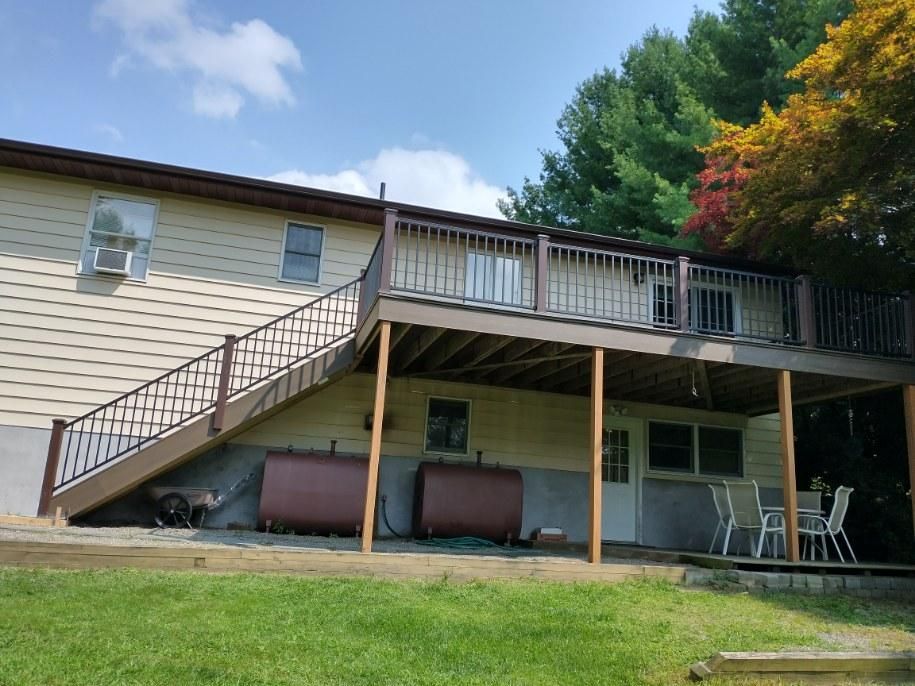 A wooden deck with a fence and trees in the background