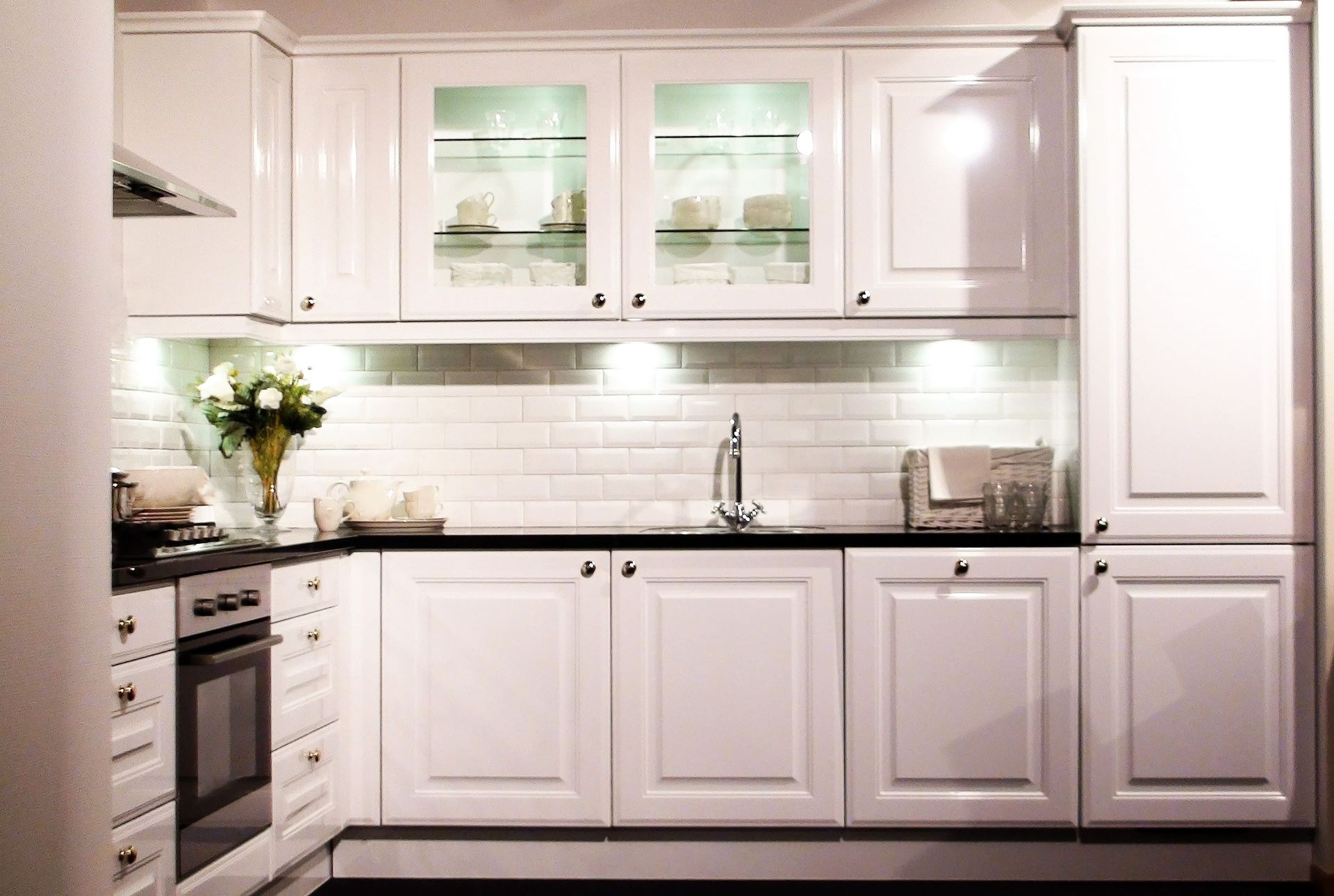 A kitchen with white cabinets and black counter tops