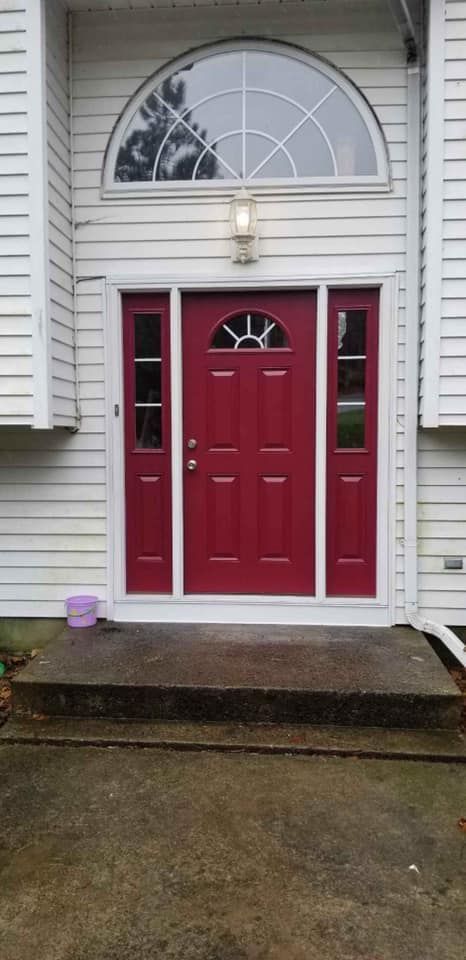 A man is standing on a ladder painting the side of a house.