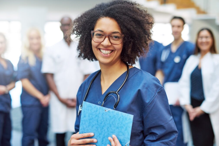 A medical professional stands holding a chart in front of a row of other medical professionals.