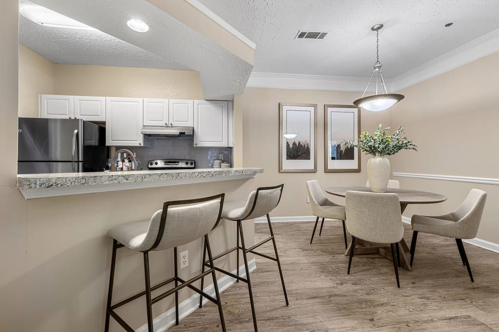 Apartment kitchen with spacious island and dining room with a table and chairs at Marquis at Sugarloaf in Duluth, GA.