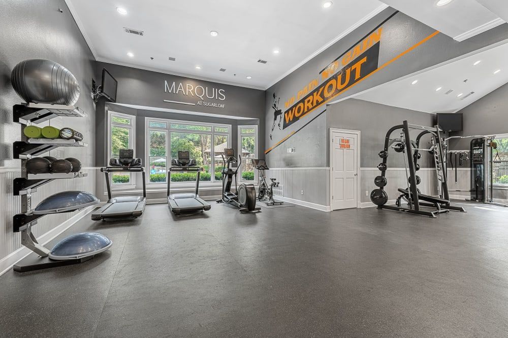 An apartment fitness center with a treadmill, exercise equipment, and a large mirror at Marquis at Sugarloaf in Duluth, GA.