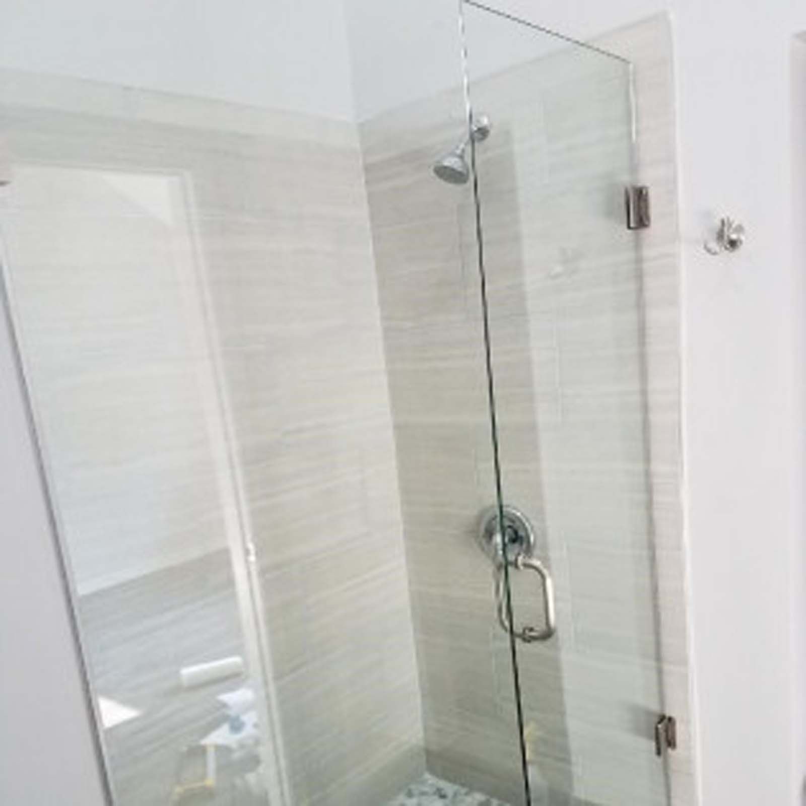 Glass shower enclosure with silver fixtures in a modern bathroom.