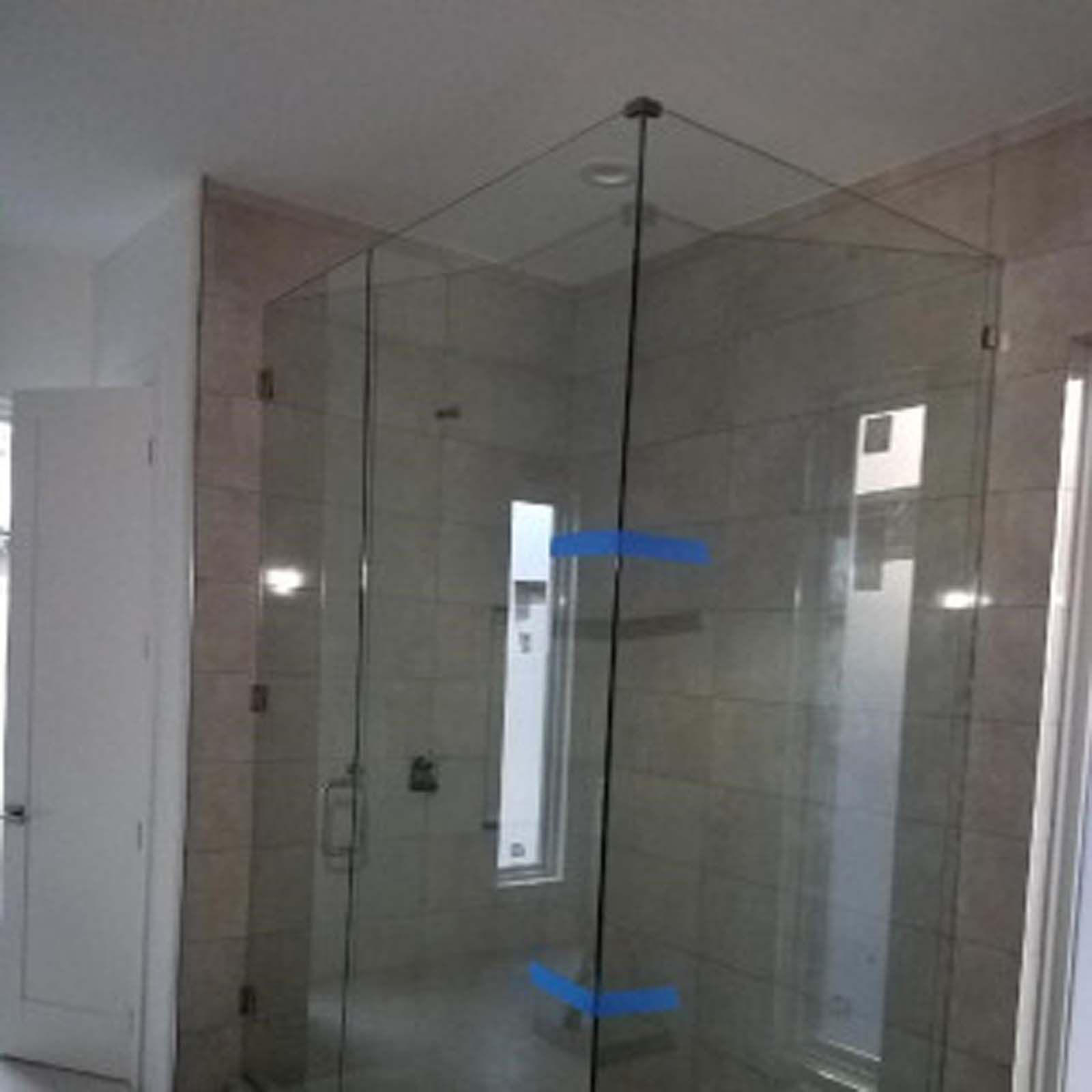 Glass shower enclosure in a bathroom with tiled walls.