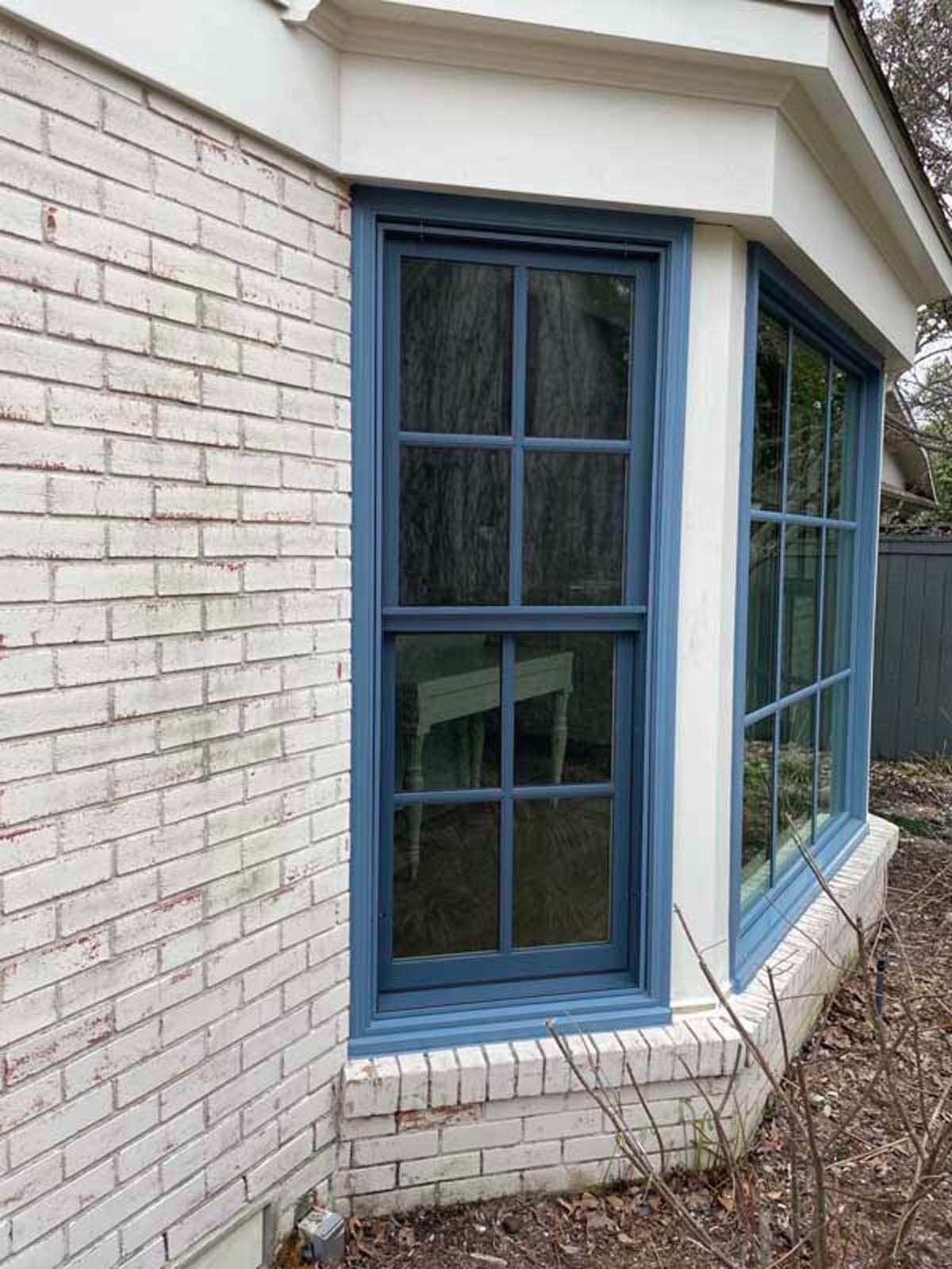 Bay windows with blue trim and white brick exterior.
