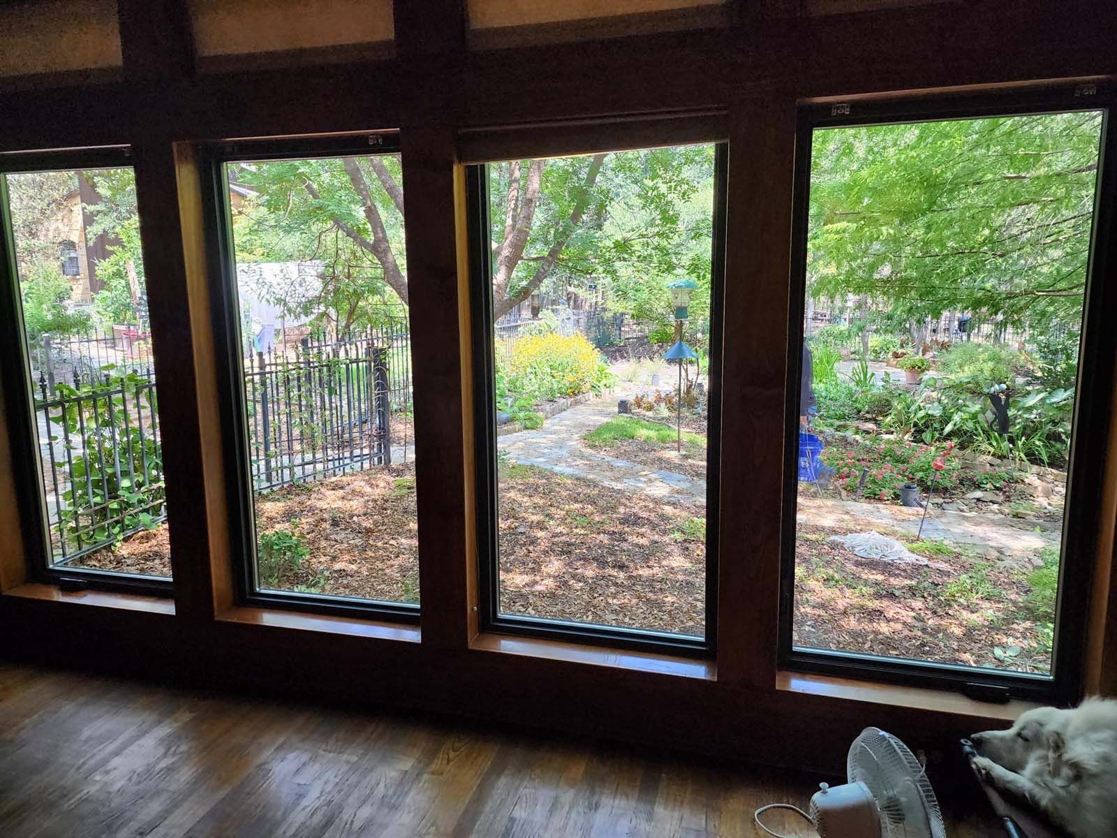 Wooden framed windows overlooking a garden. Brown wooden floors and framing.