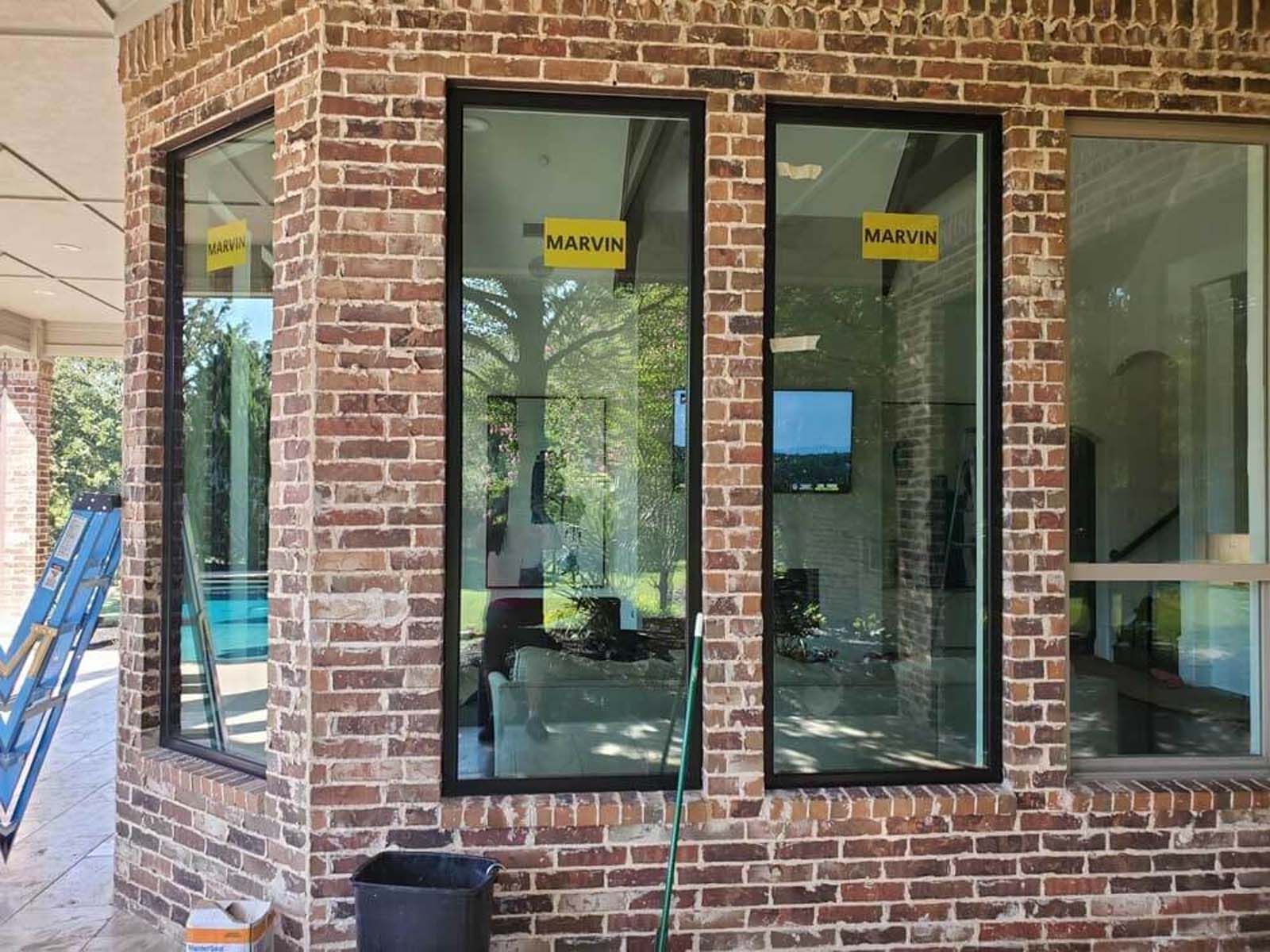 Brick building with three tall windows; construction site with ladder, bucket, and hose.