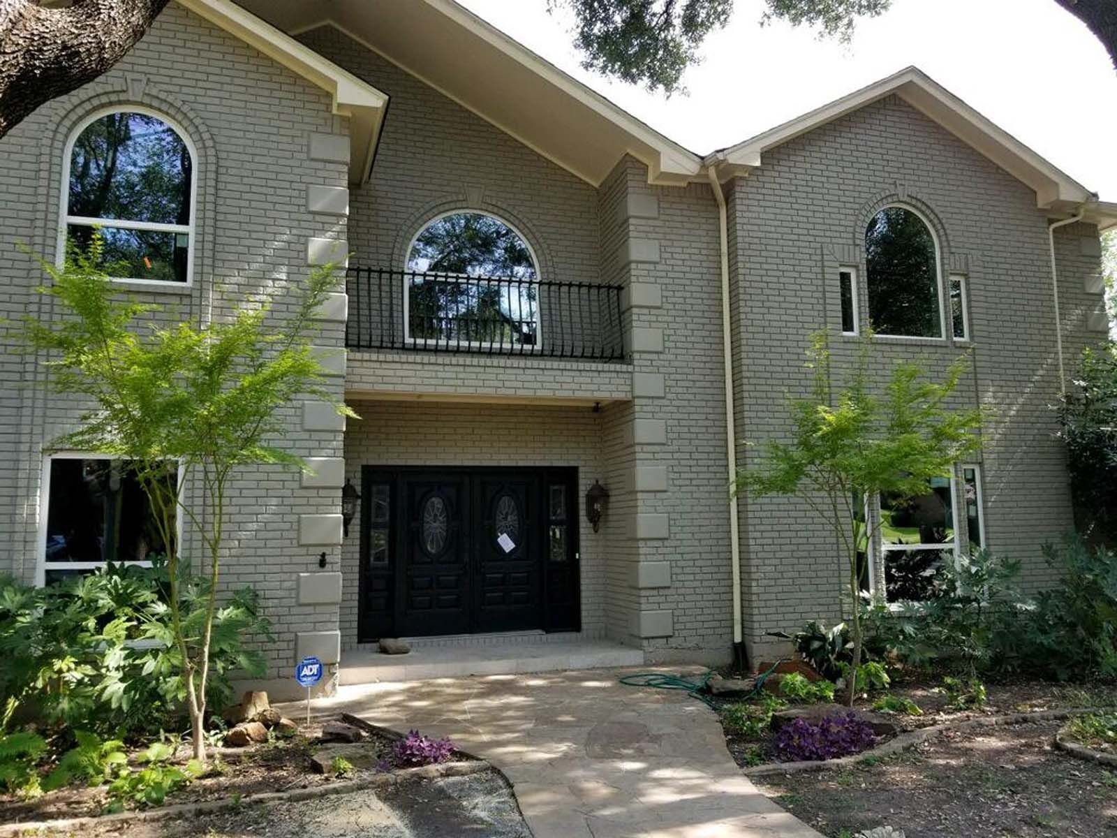 Two-story brick house with arched windows and black double doors.