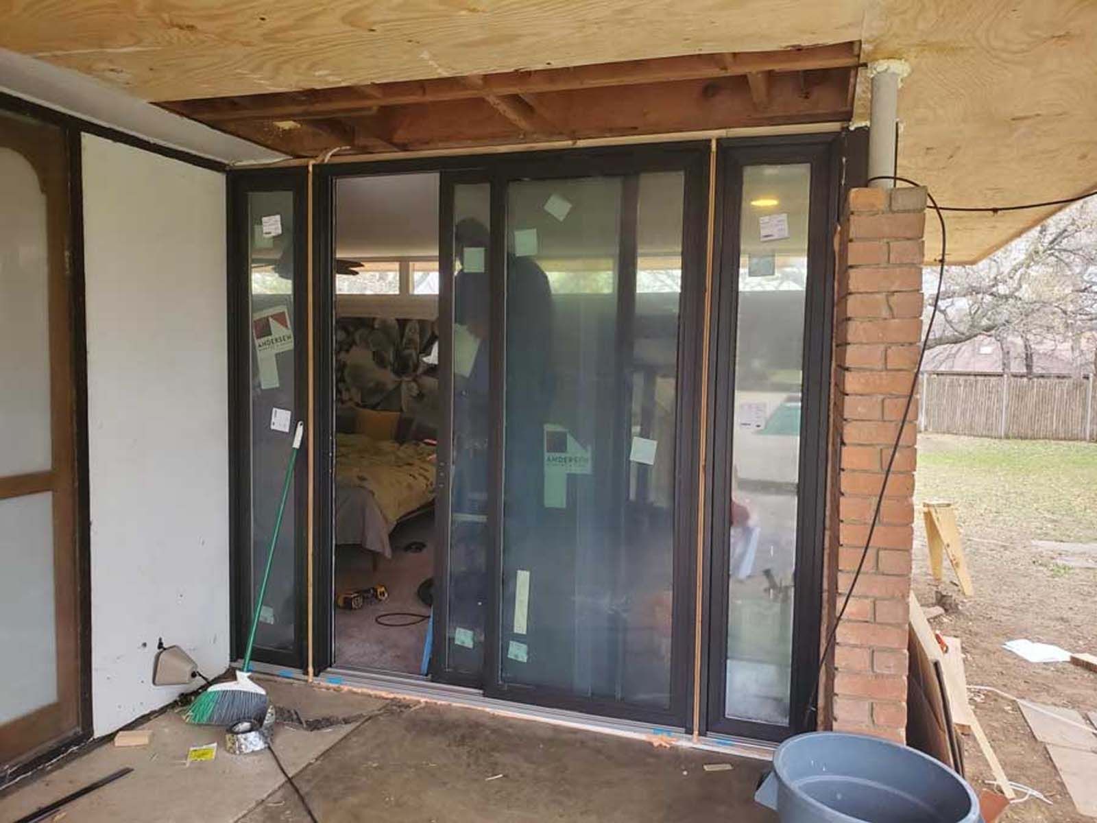 New sliding glass doors being installed on a patio, under a covered roof.