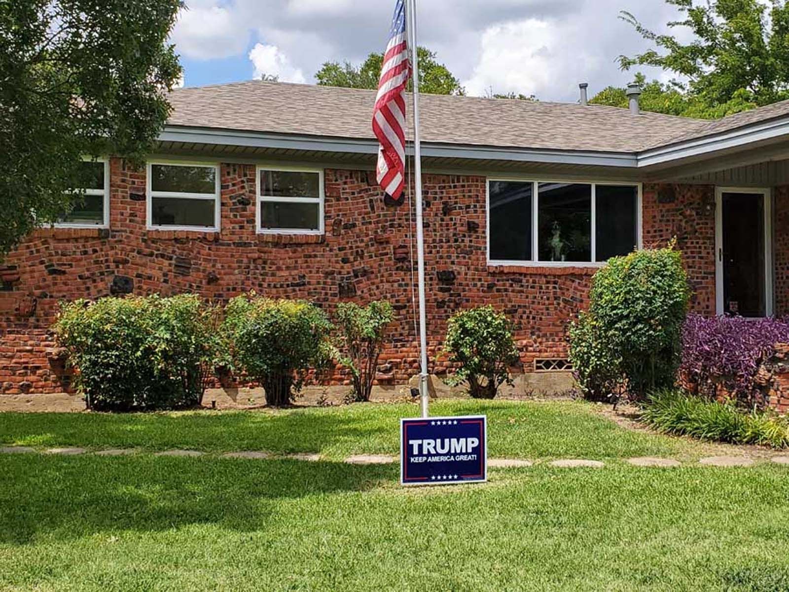 Brick house with American flag and Trump campaign sign in the yard.