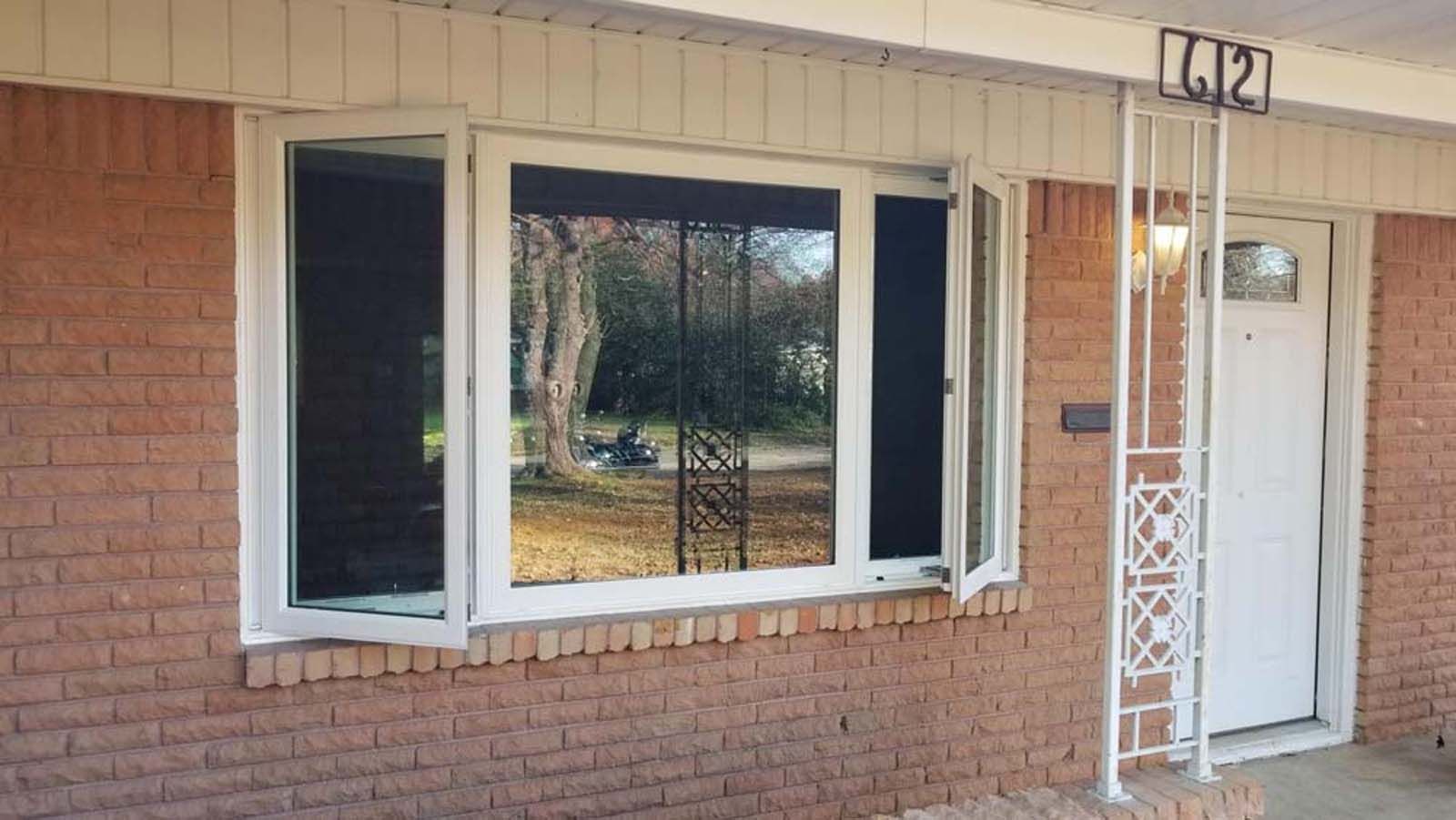 Brick house with white trim, bay window with open side panels, and white front door under a porch.