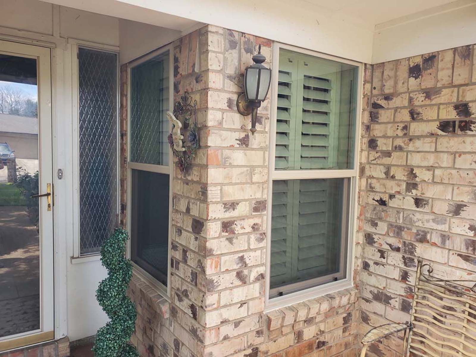 Brick building exterior with window, shutters, and door.