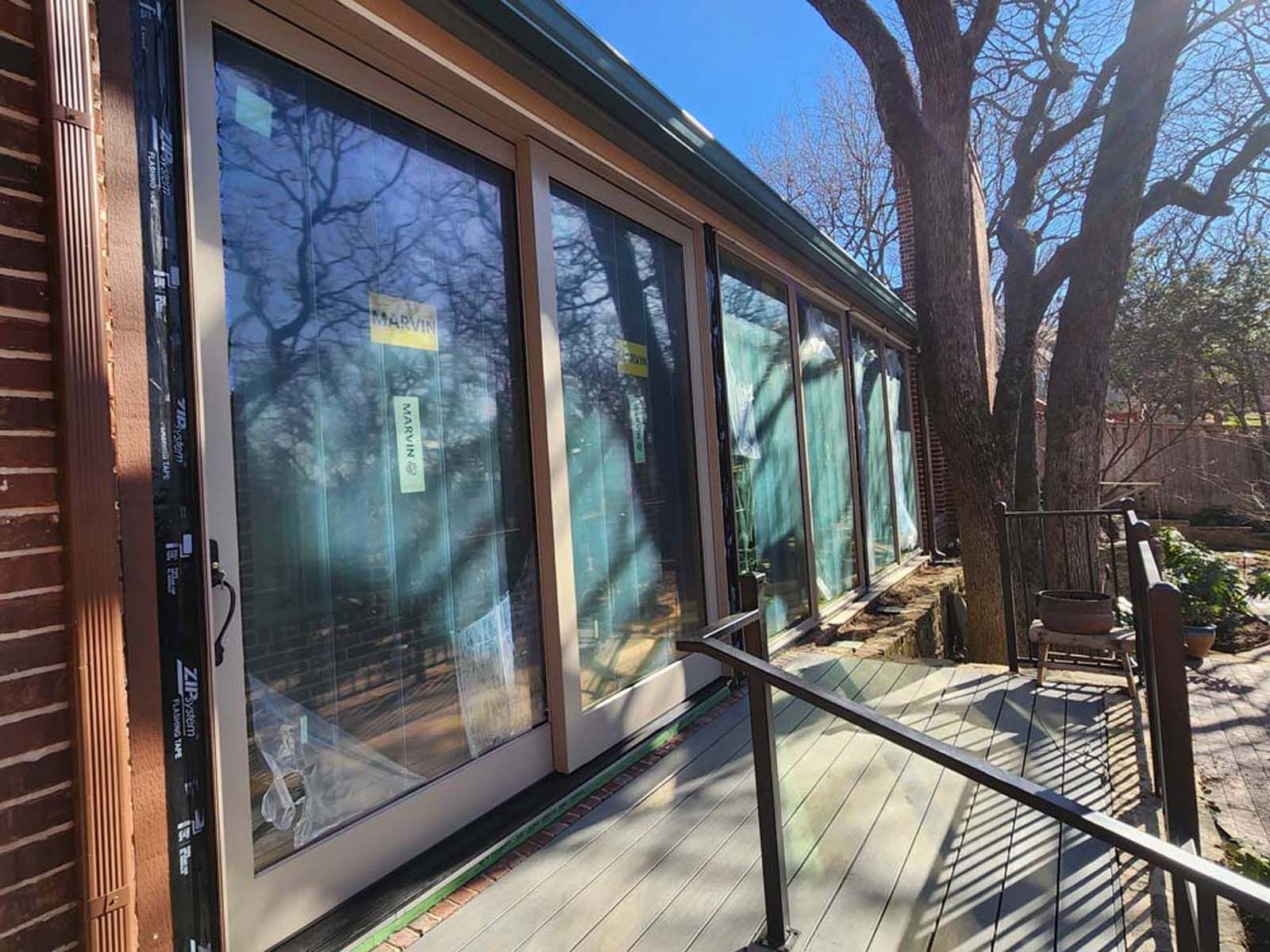 Glass doors on a building with a wooden deck and a tree.