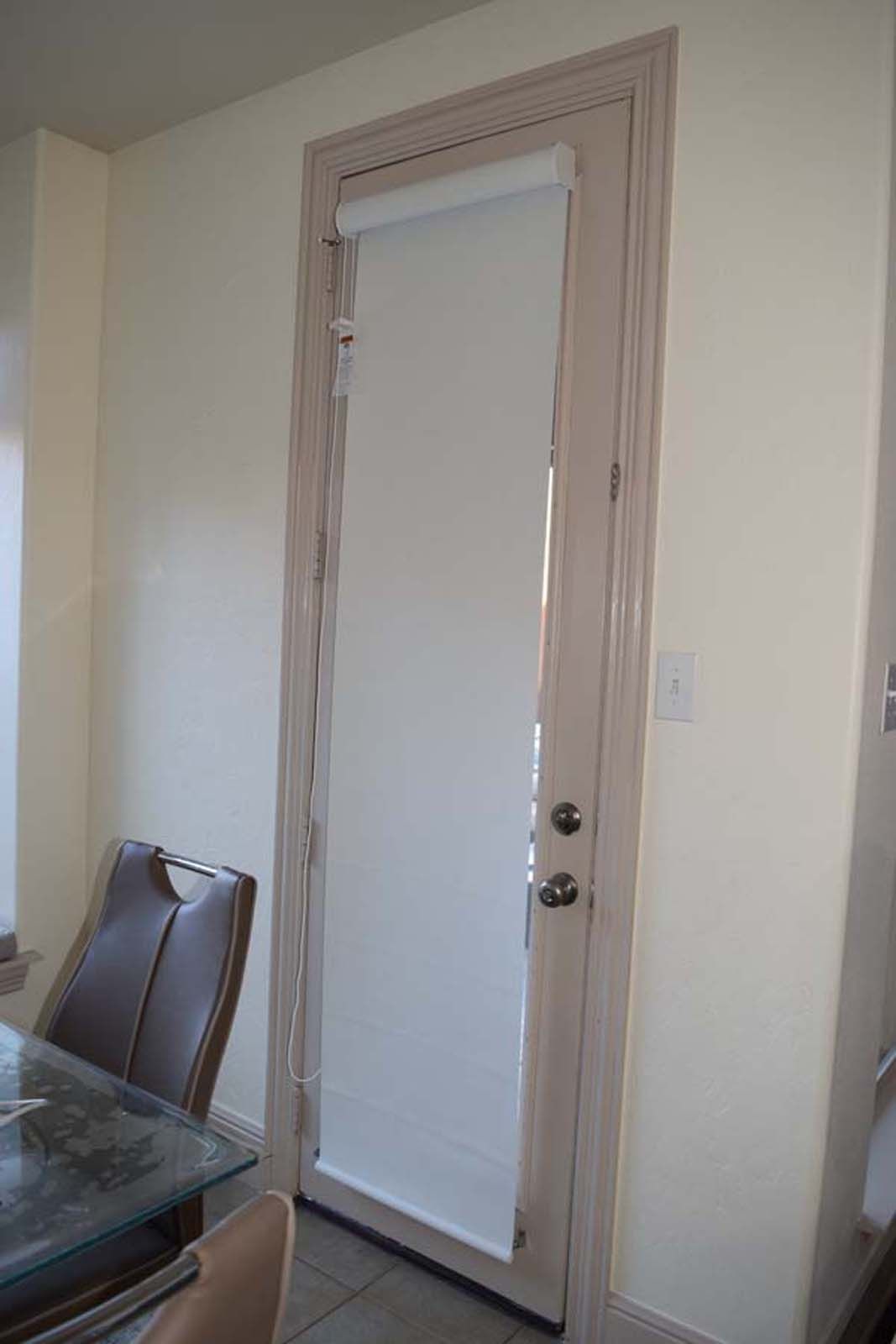 Door with white shade, neutral-colored frame, and surrounding cream-colored walls.