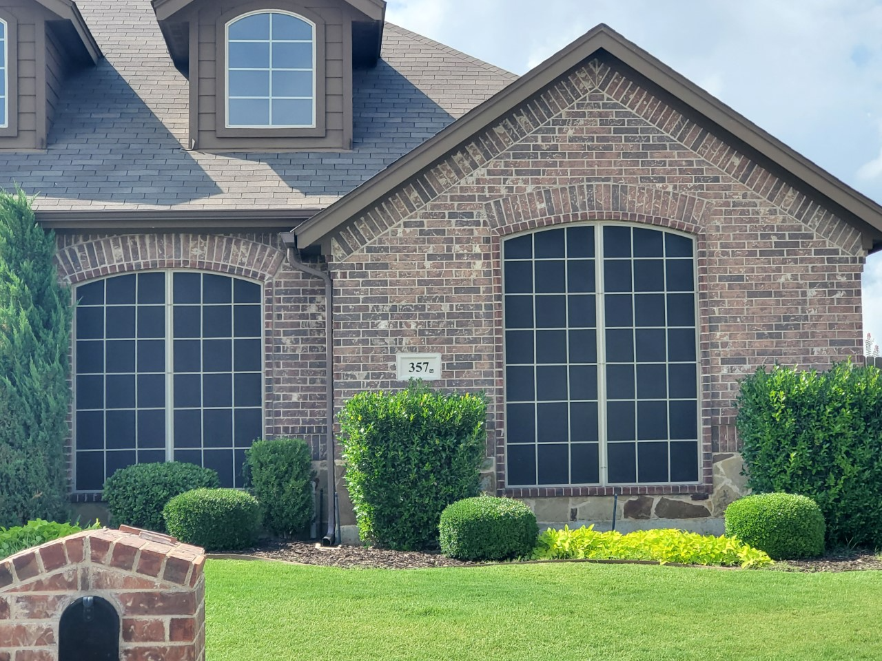 Brick house with arched windows and green landscaping.