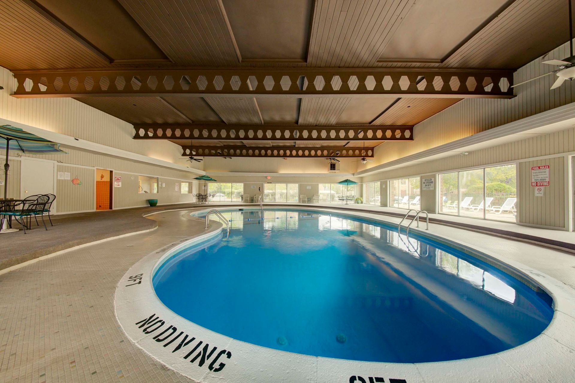 a large indoor swimming pool with a no diving sign on the edge at Camelot Place.