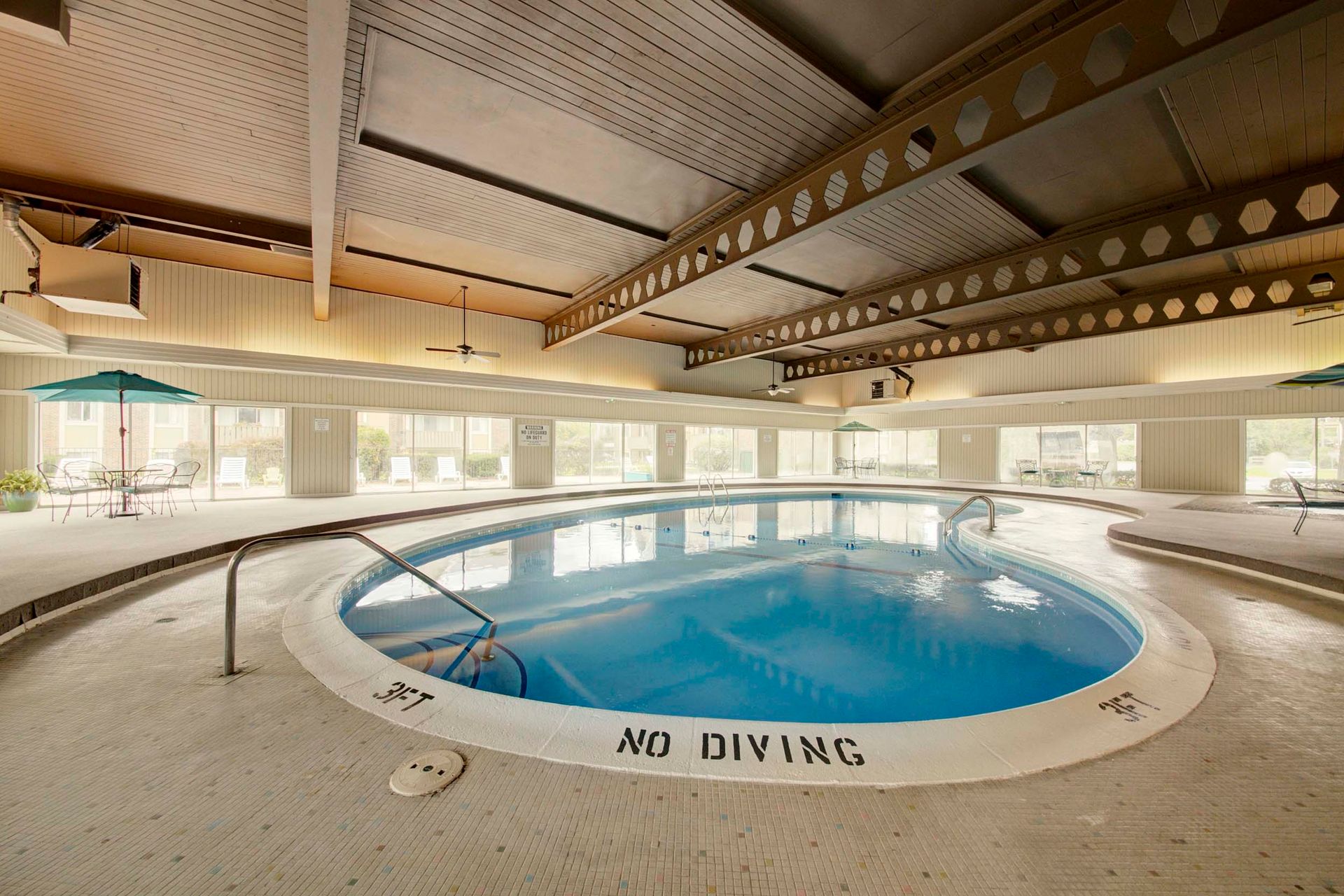 a large indoor swimming pool with a no diving sign at Camelot Place.