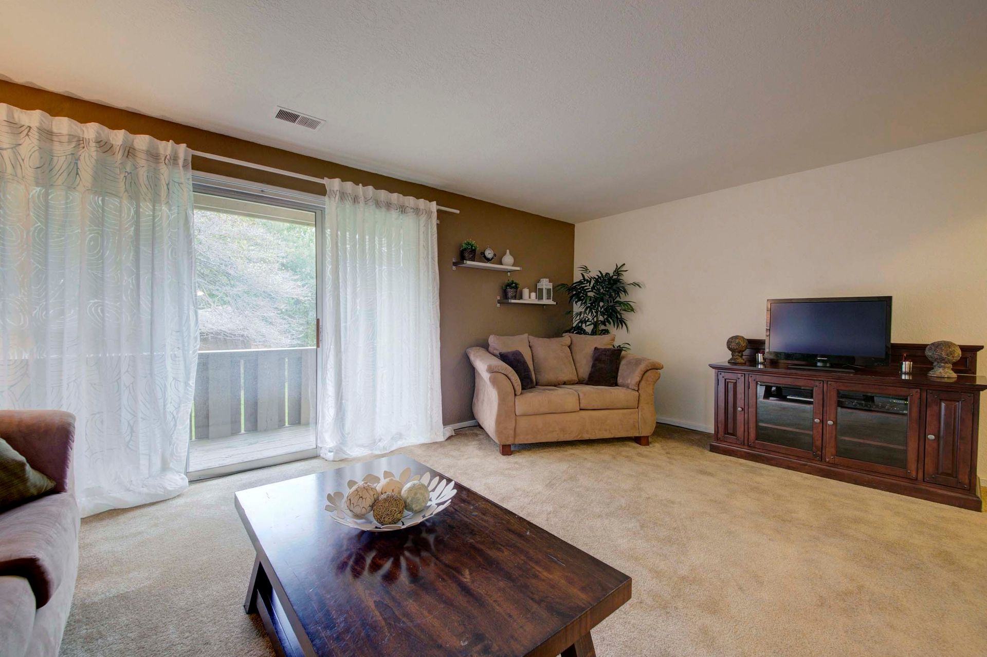a living room with a couch , chair , coffee table and television at Camelot Place.
