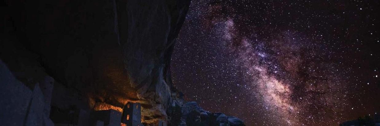 A night sky filled with lots of stars and a building in the foreground.