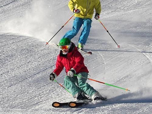 A man and a child are skiing down a snow covered slope.