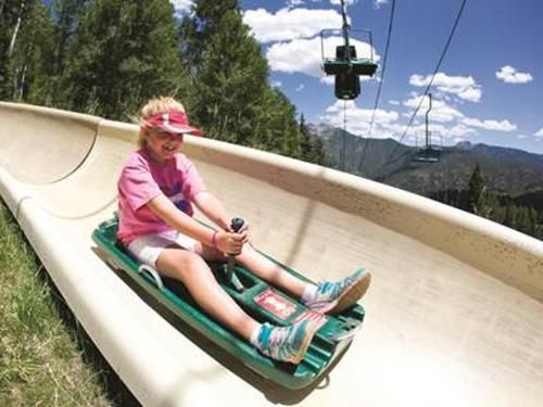 A young girl is riding down a snow slide.