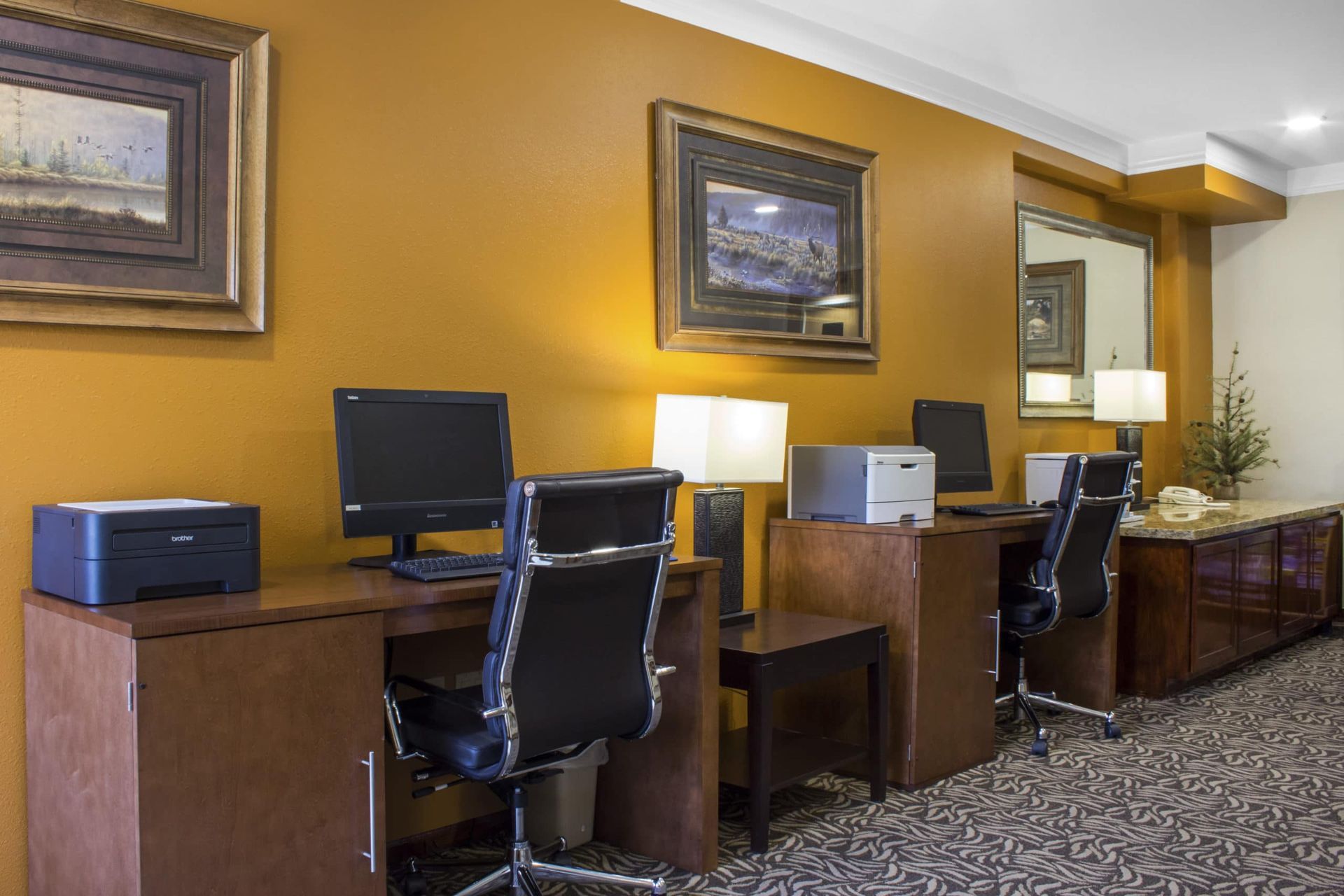 A hotel room with a computer desk and chairs