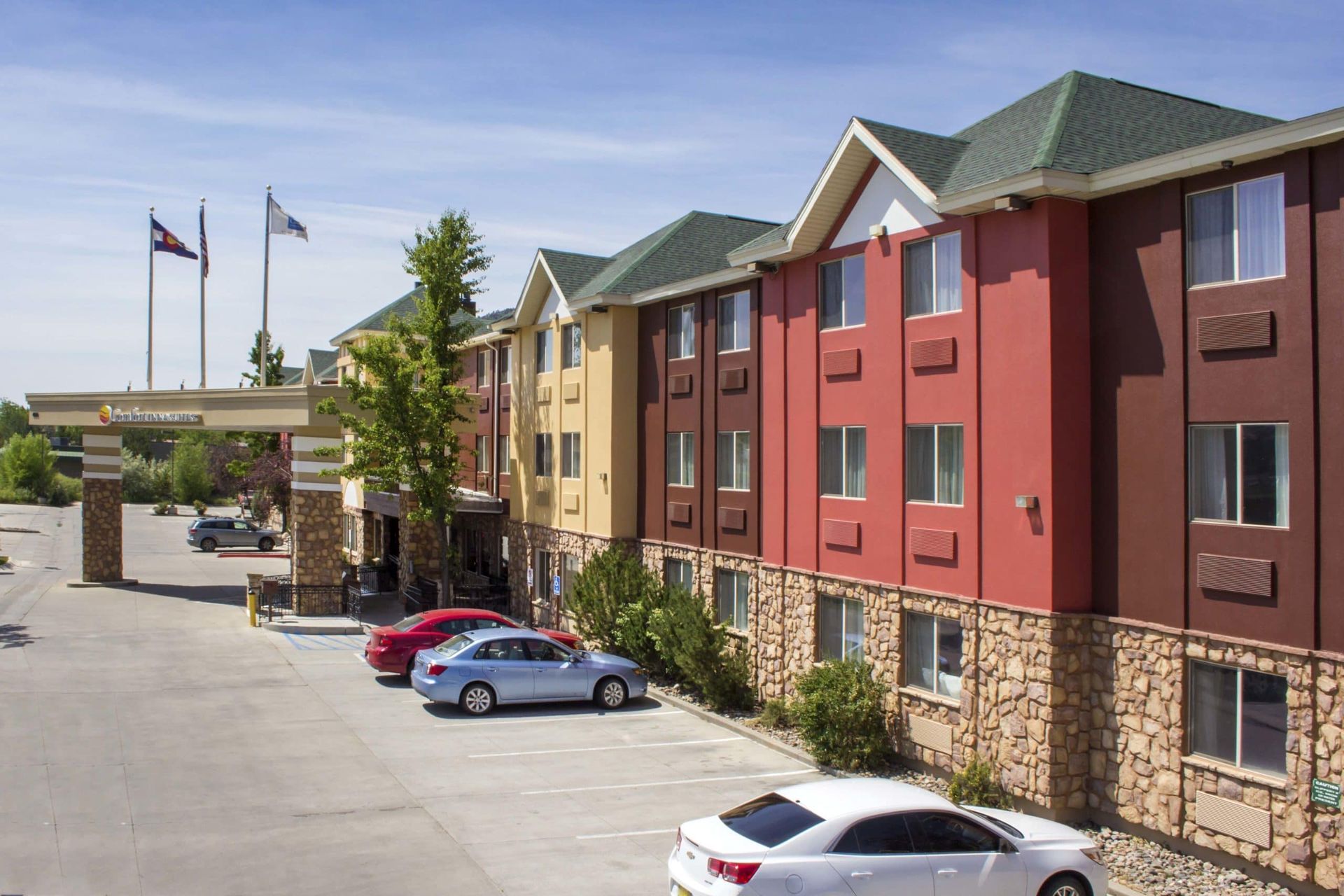 A white car is parked in front of a hotel.