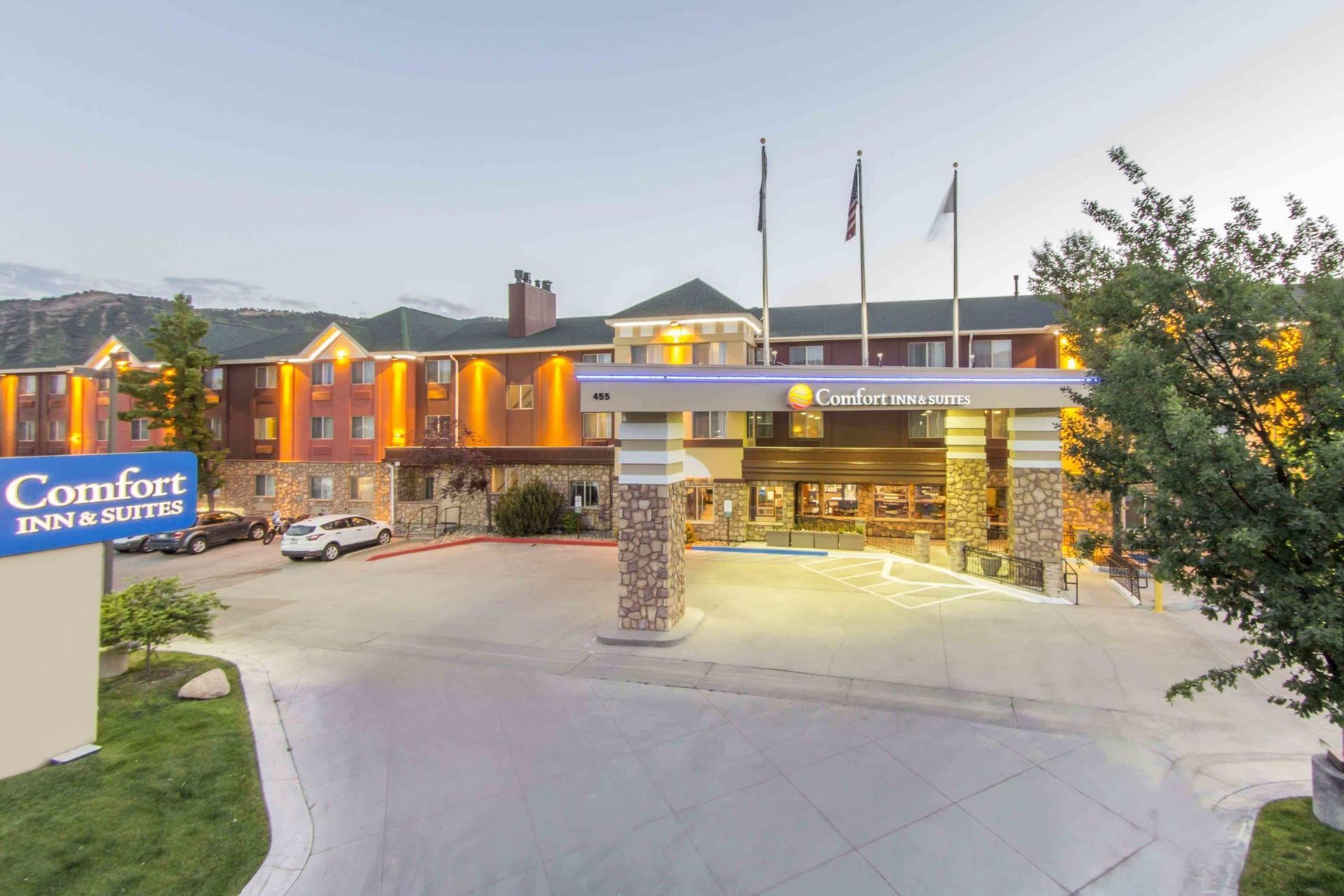 A large hotel with a lot of cars parked in front of it.