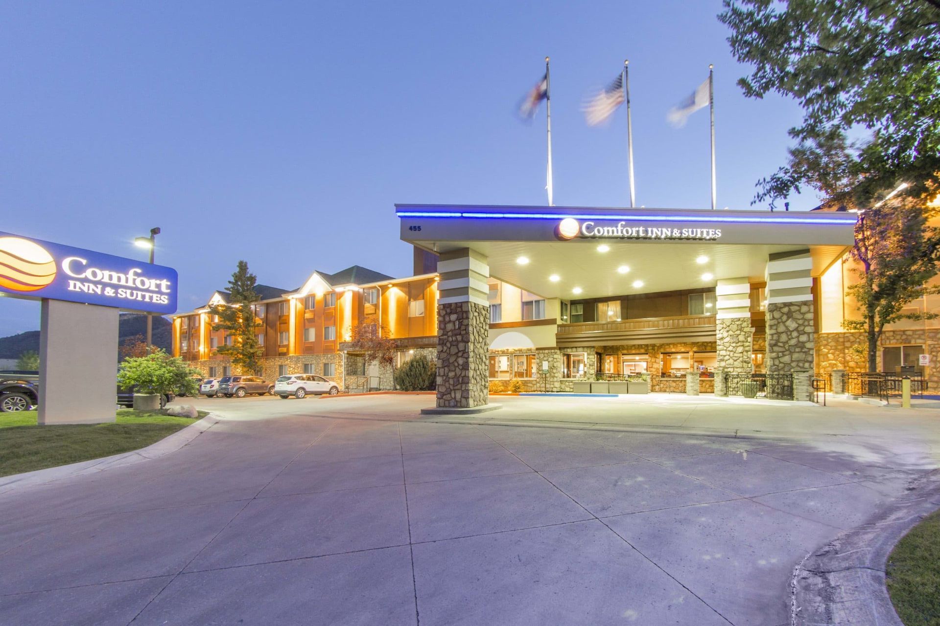 A large hotel with a lot of cars parked in front of it at night.